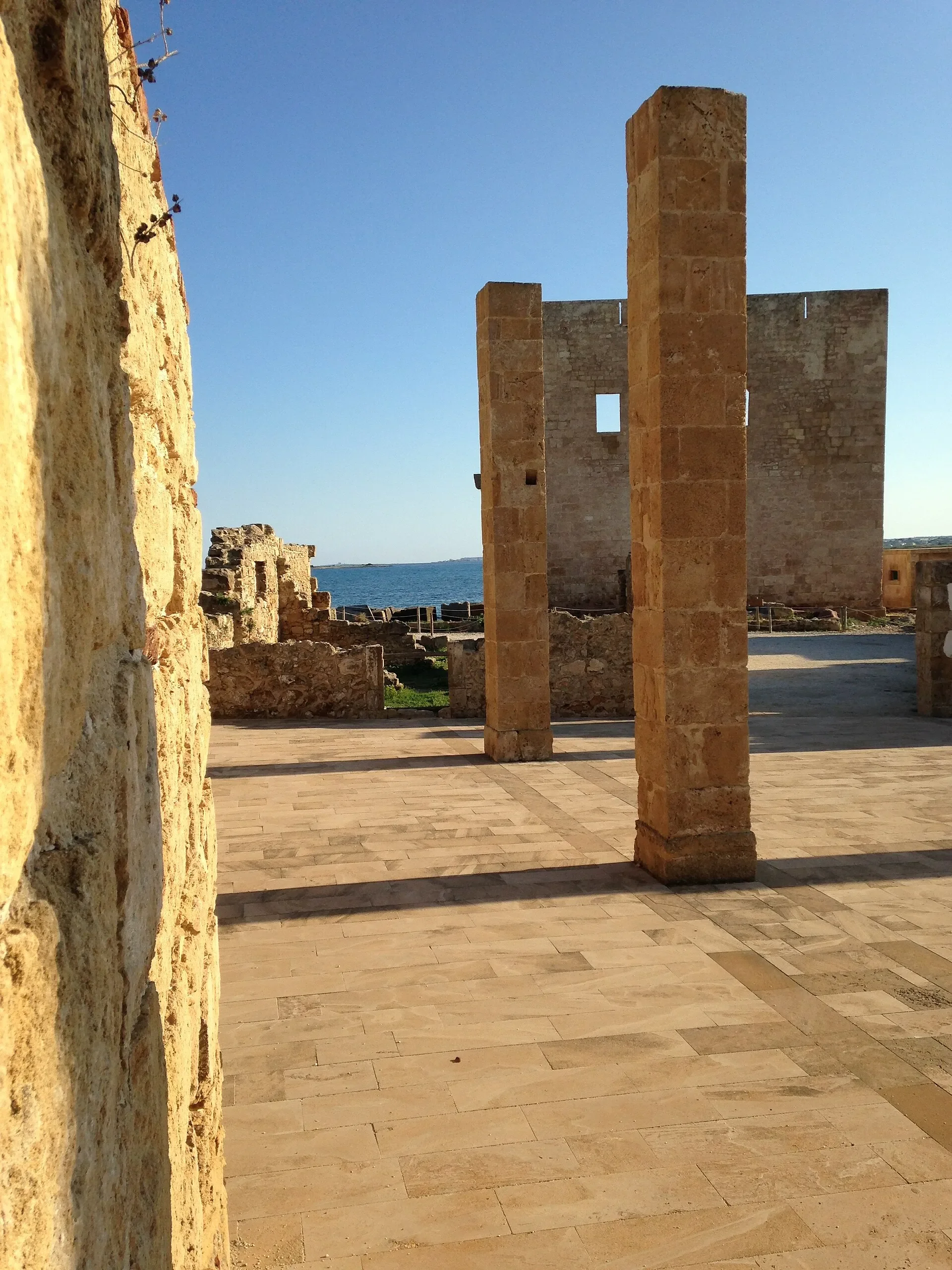 Stone pillars and ruins at the historic Tonnara di Vendicari, with the sea visible beyond