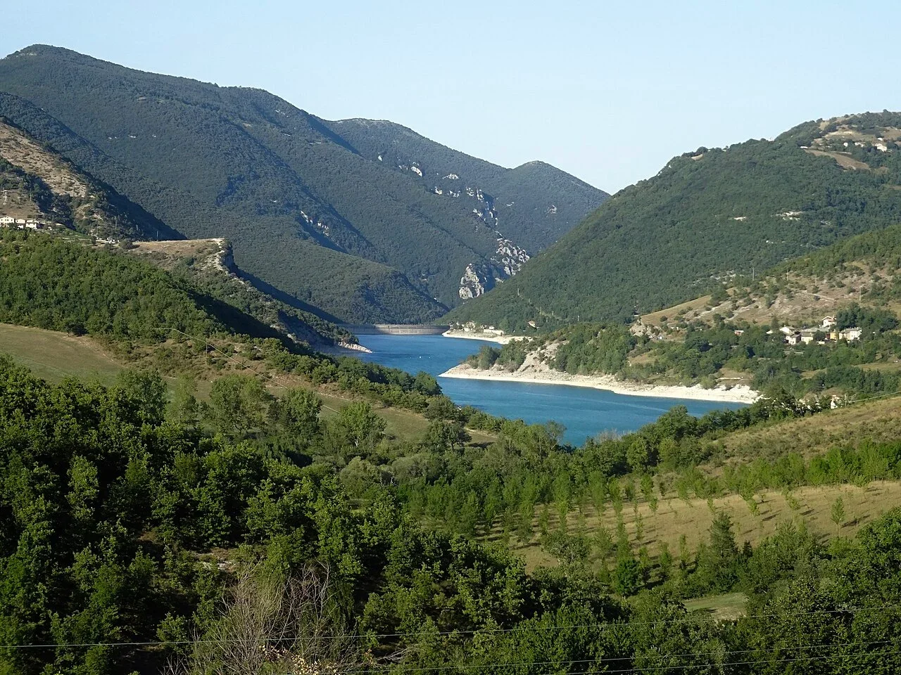Lago di Fiastra winding through a valley of wooded mountain slopes