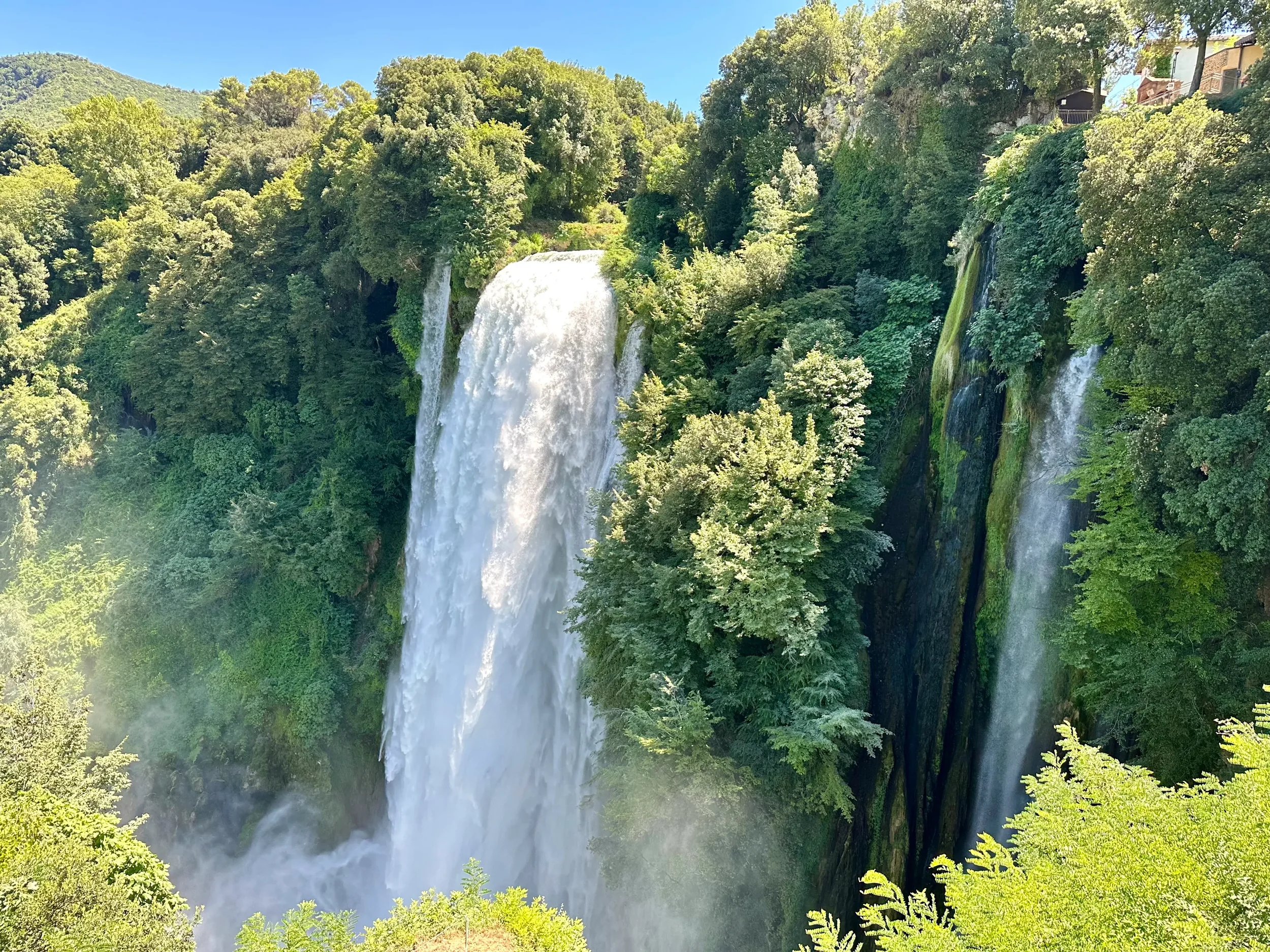 Close view of the main drop of Marmore Falls surrounded by trees and moss-covered rock