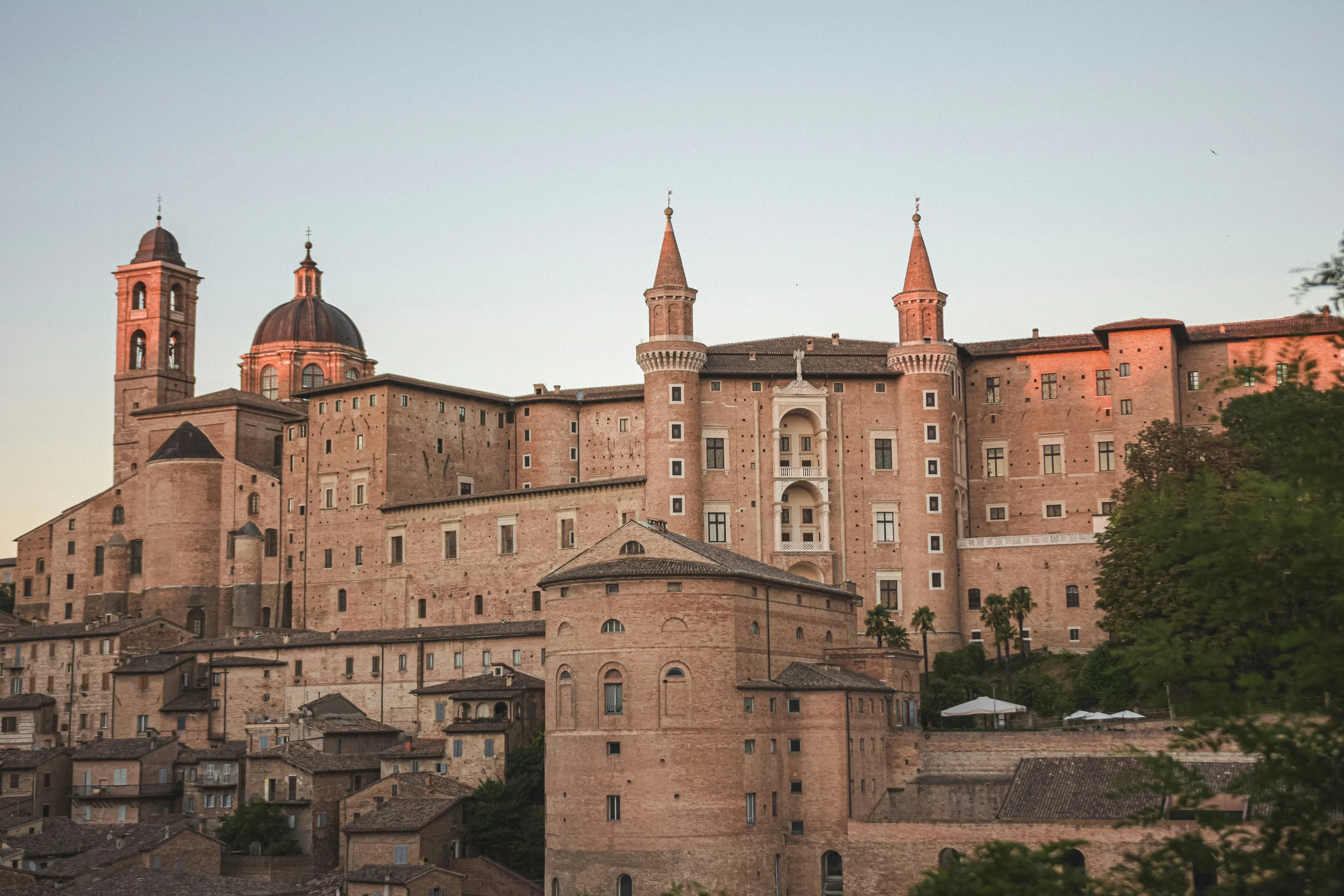 Ducal Palace and cathedral rising above the historic rooftops of Urbino in Le Marche, Italy