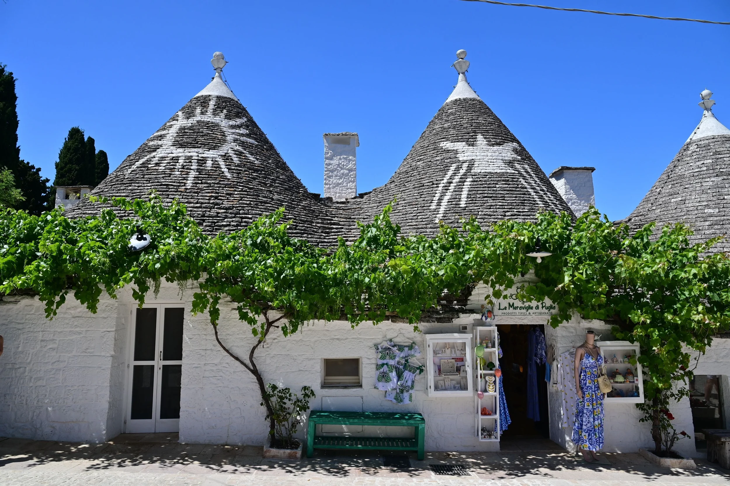 Traditional trulli houses surrounded by greenery in the Valle d’Itria, Puglia, Italy