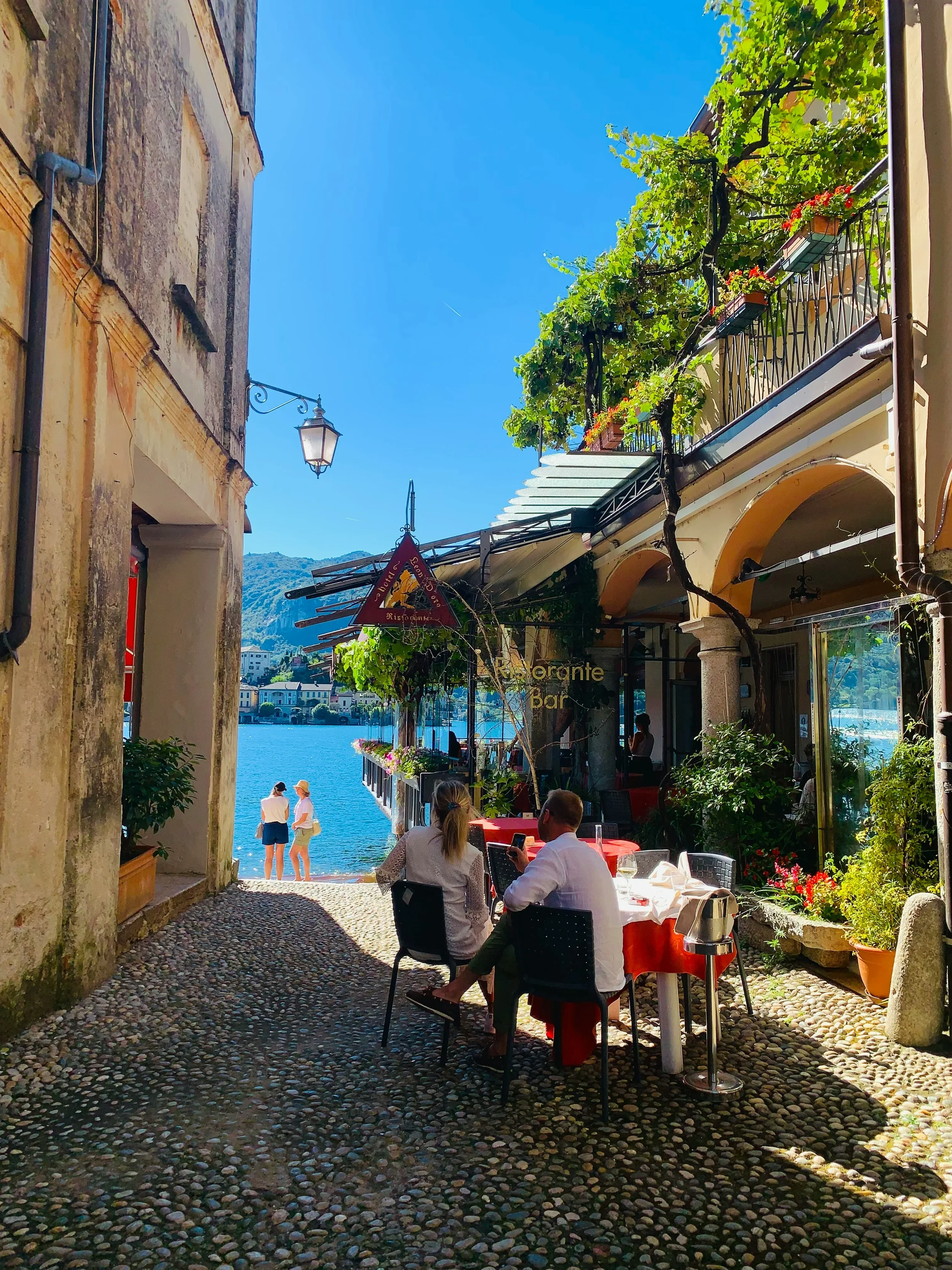A cobbled lane and restaurant terrace opening onto Lake Orta in Orta San Giulio.