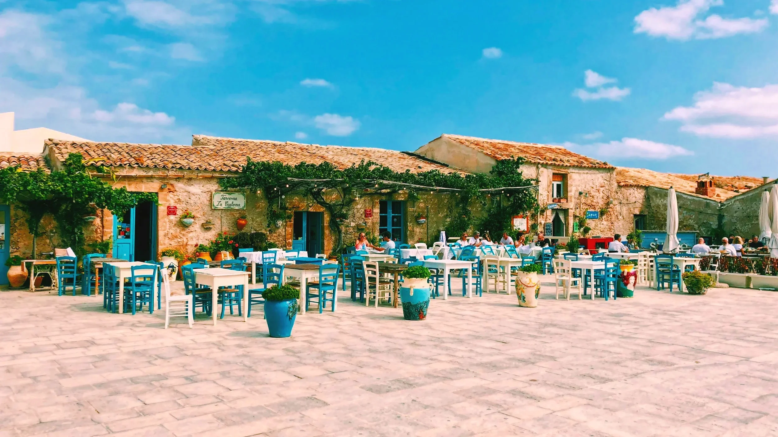 Blue and white restaurant tables in Piazza Regina Margherita in the fishing village of Marzamemi, Sicily, Italy