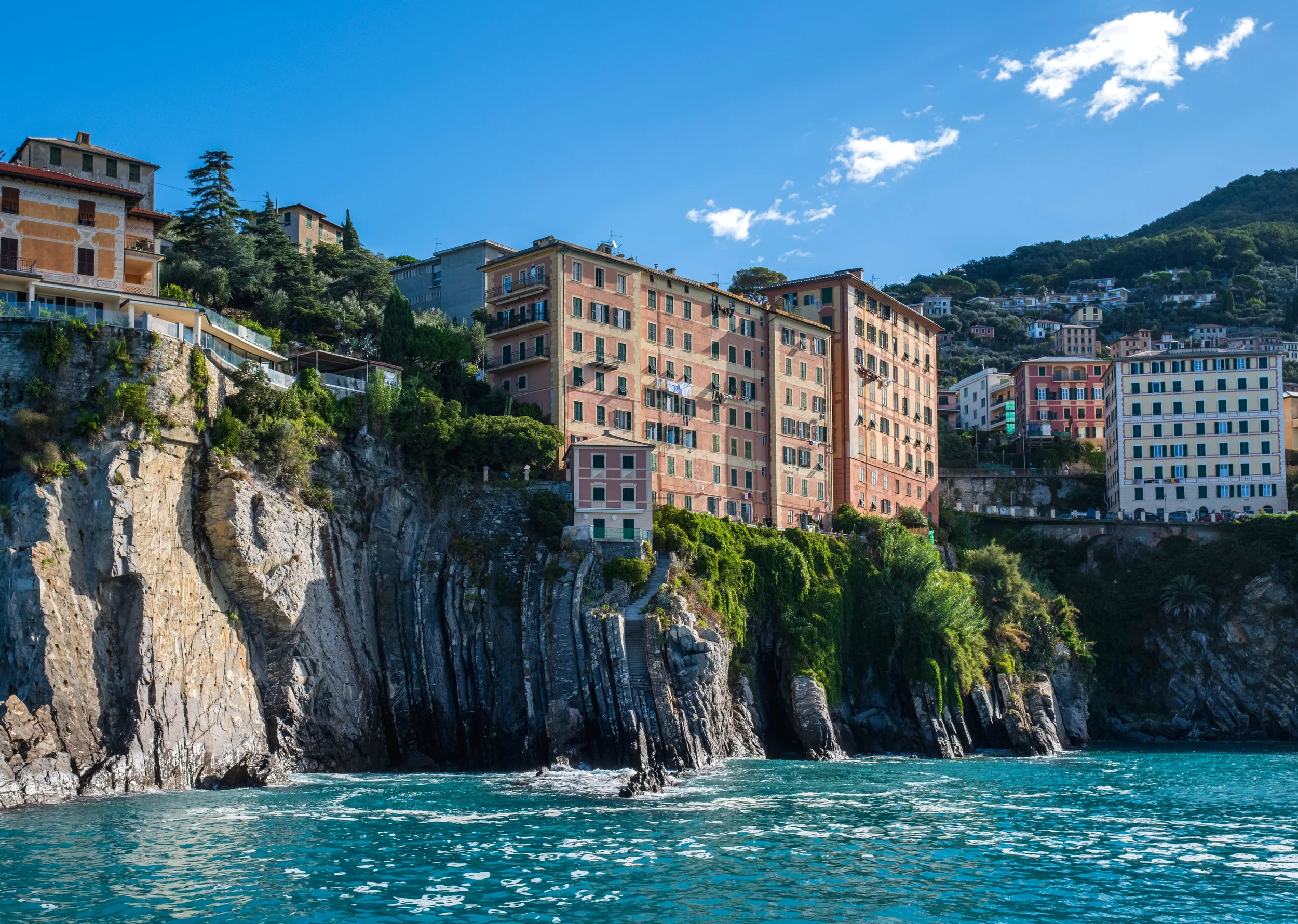 Pastel waterfront houses above steep rocky cliffs on the Ligurian coast, Italy