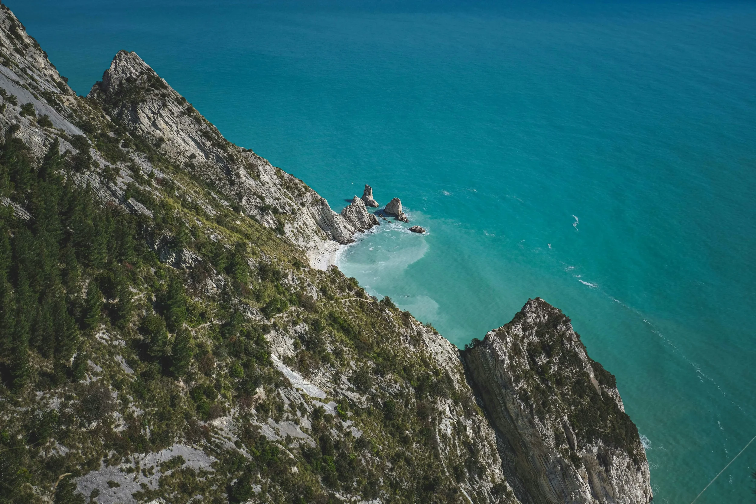 A steep view down the pale Conero cliffs towards Due Sorelle beach and its two offshore rocks