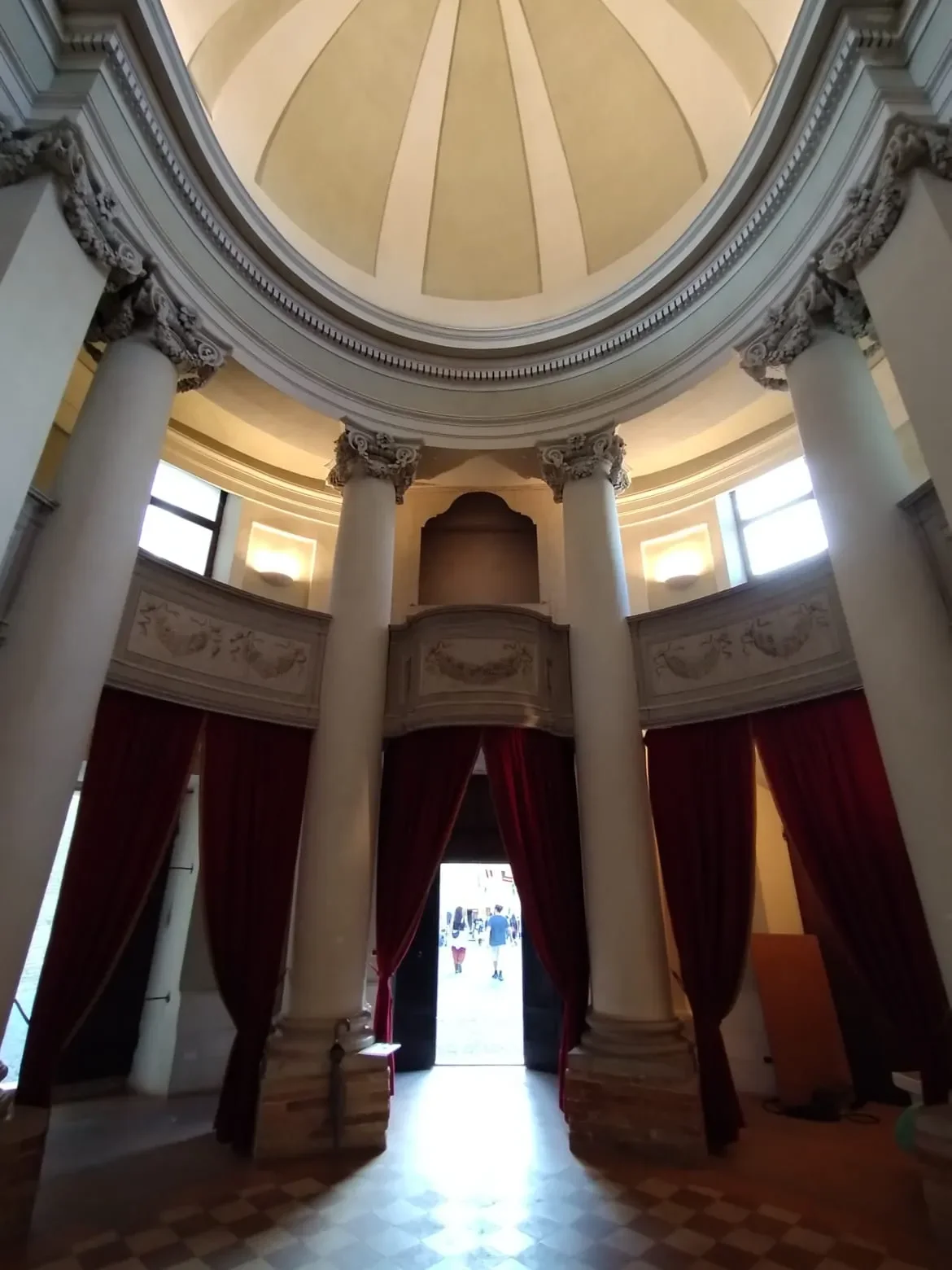 Domed interior of the church of Santissimo Sacramento in Offagna, with pale columns and red curtains