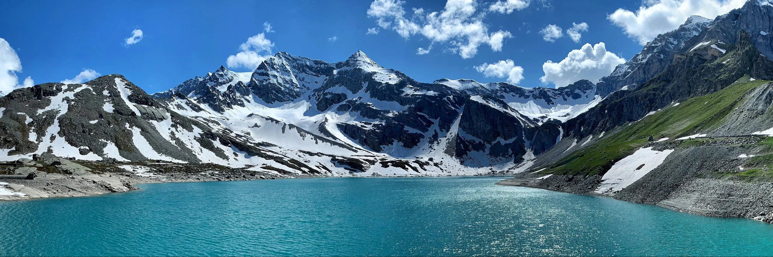 Turquoise Alpine water beneath snow-covered peaks in a high mountain basin.