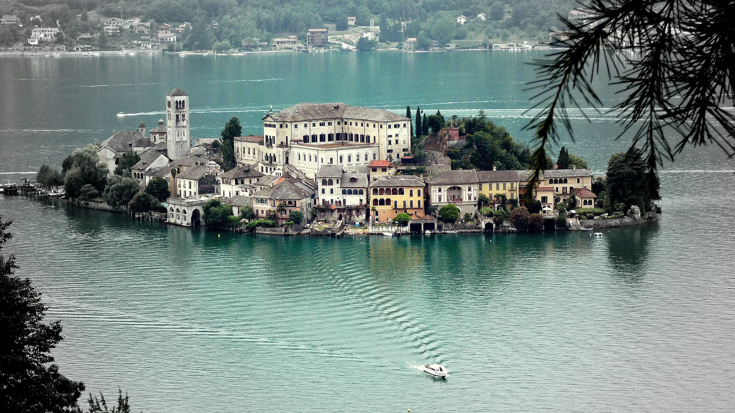 Isola San Giulio on Lake Orta, with historic waterfront buildings, a bell tower and reflections in the water, Piemonte, Italy.