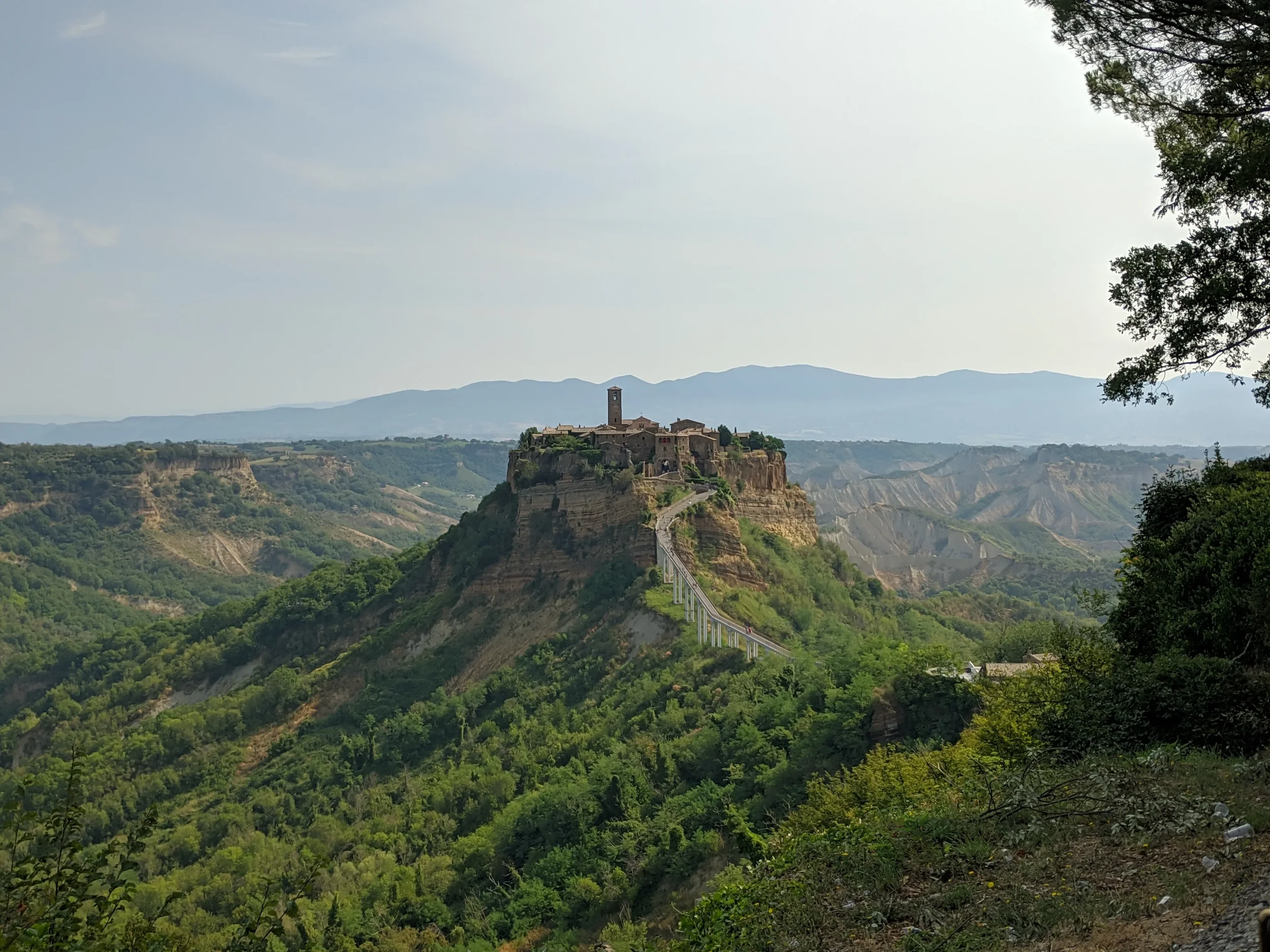Civita di Bagnoregio and its long pedestrian bridge above the wooded valley and deeply eroded clay slopes.