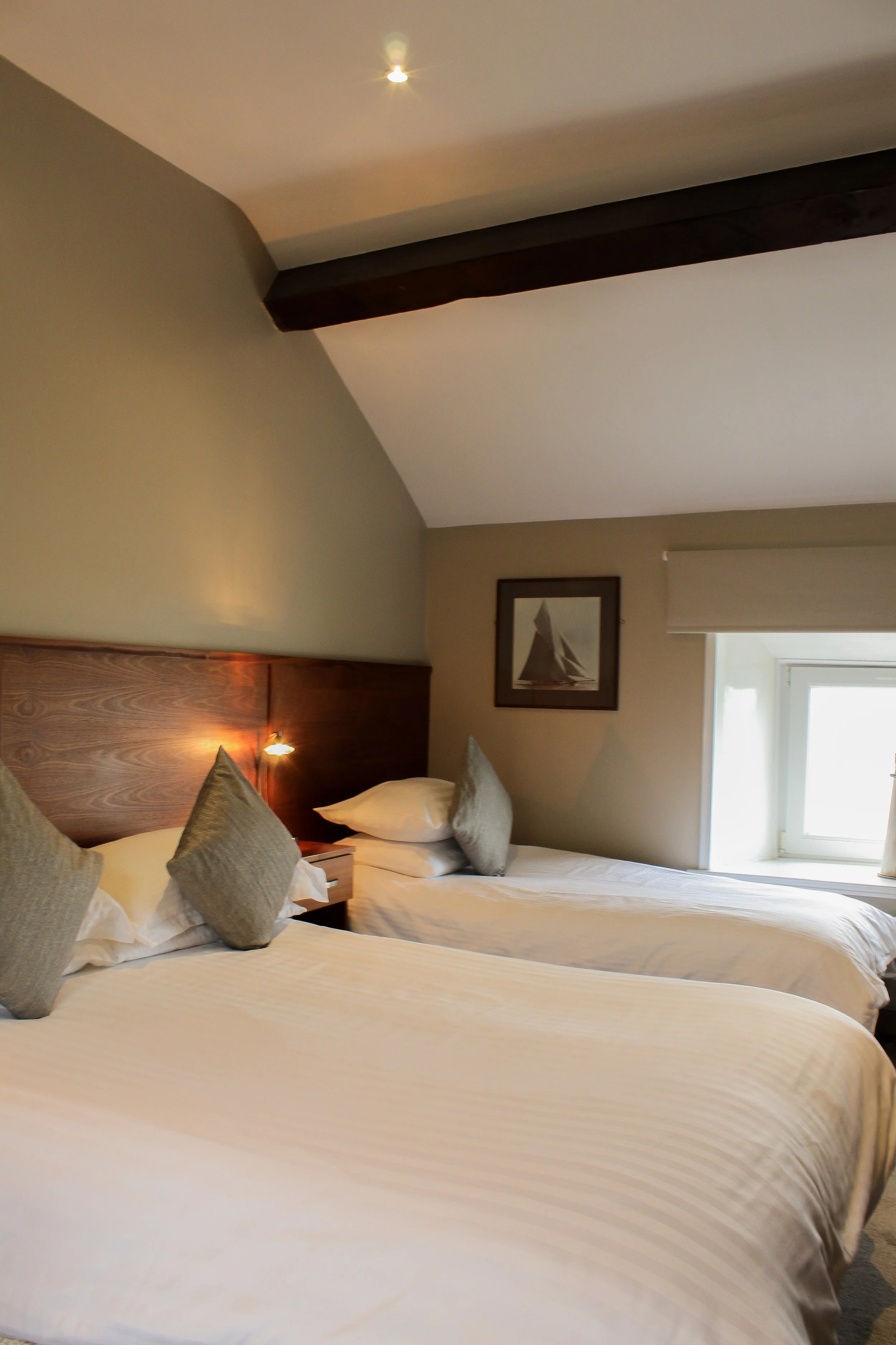 Image of double bed and single bed with beamed ceilings and sea views.