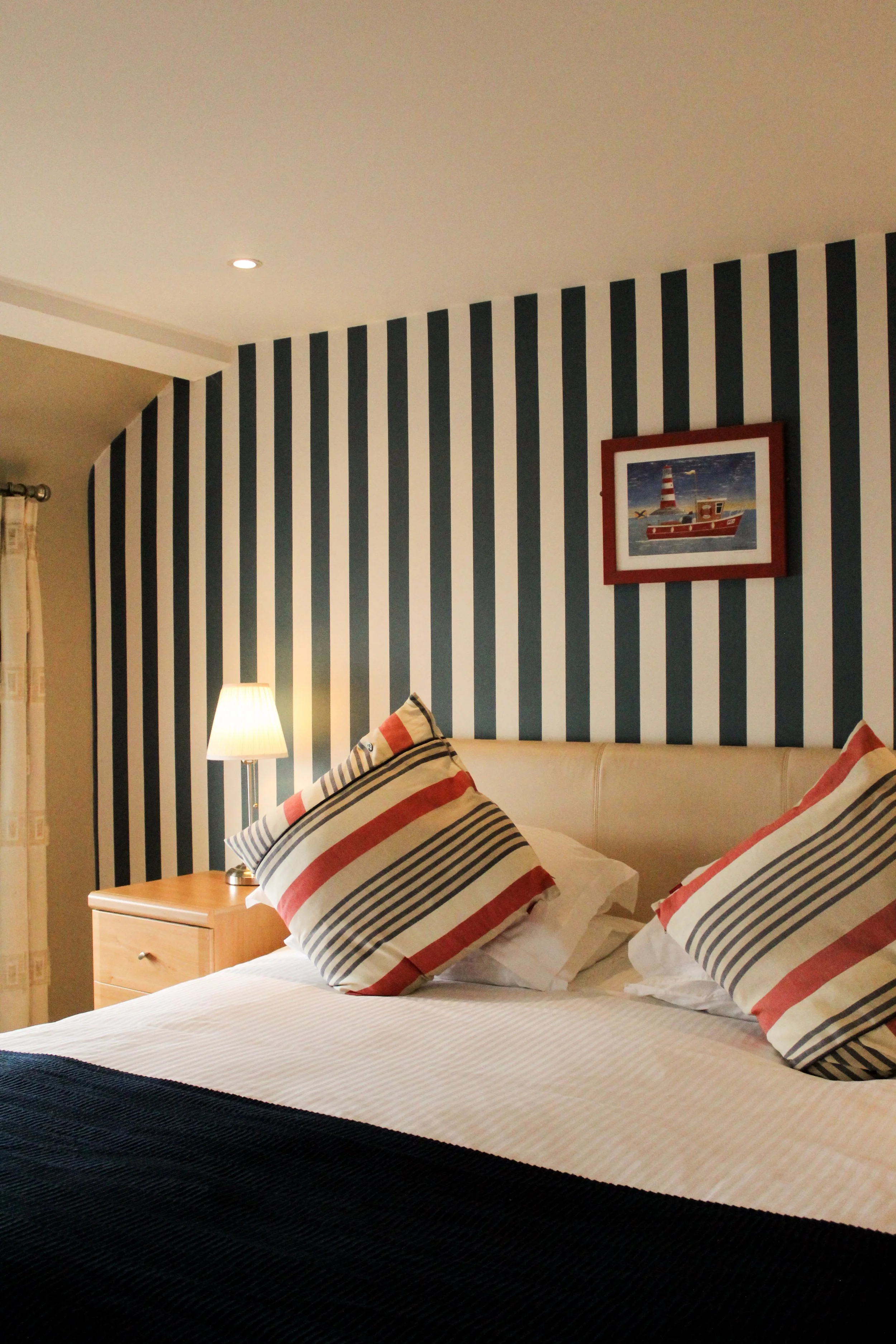 Double bed with stripe wallpaper in the background