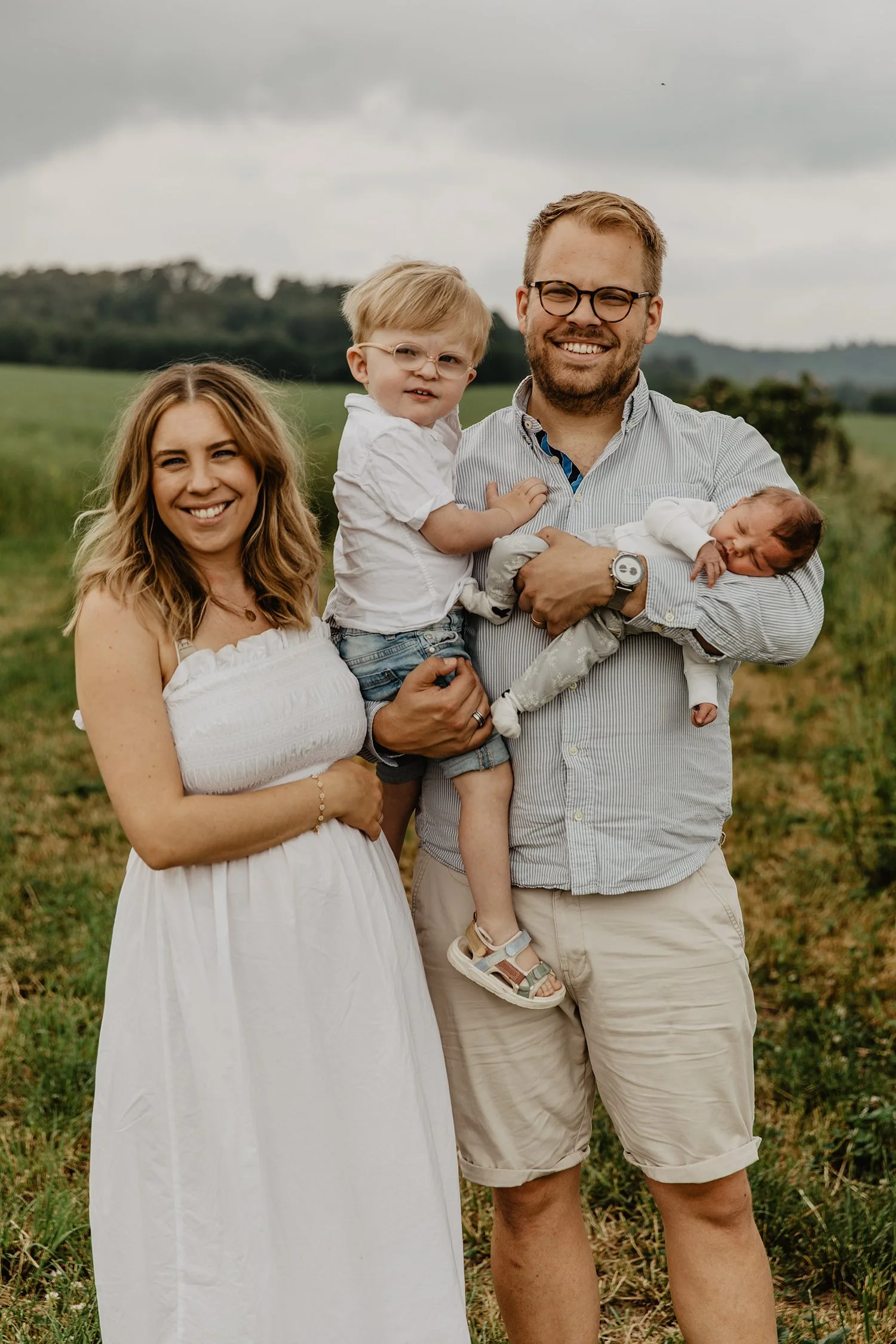 Familj på fyra ute på ett fält med gröna landskap under en familjefotografering mellan Kaxholmen och Skärstad utanför Jönköping.
