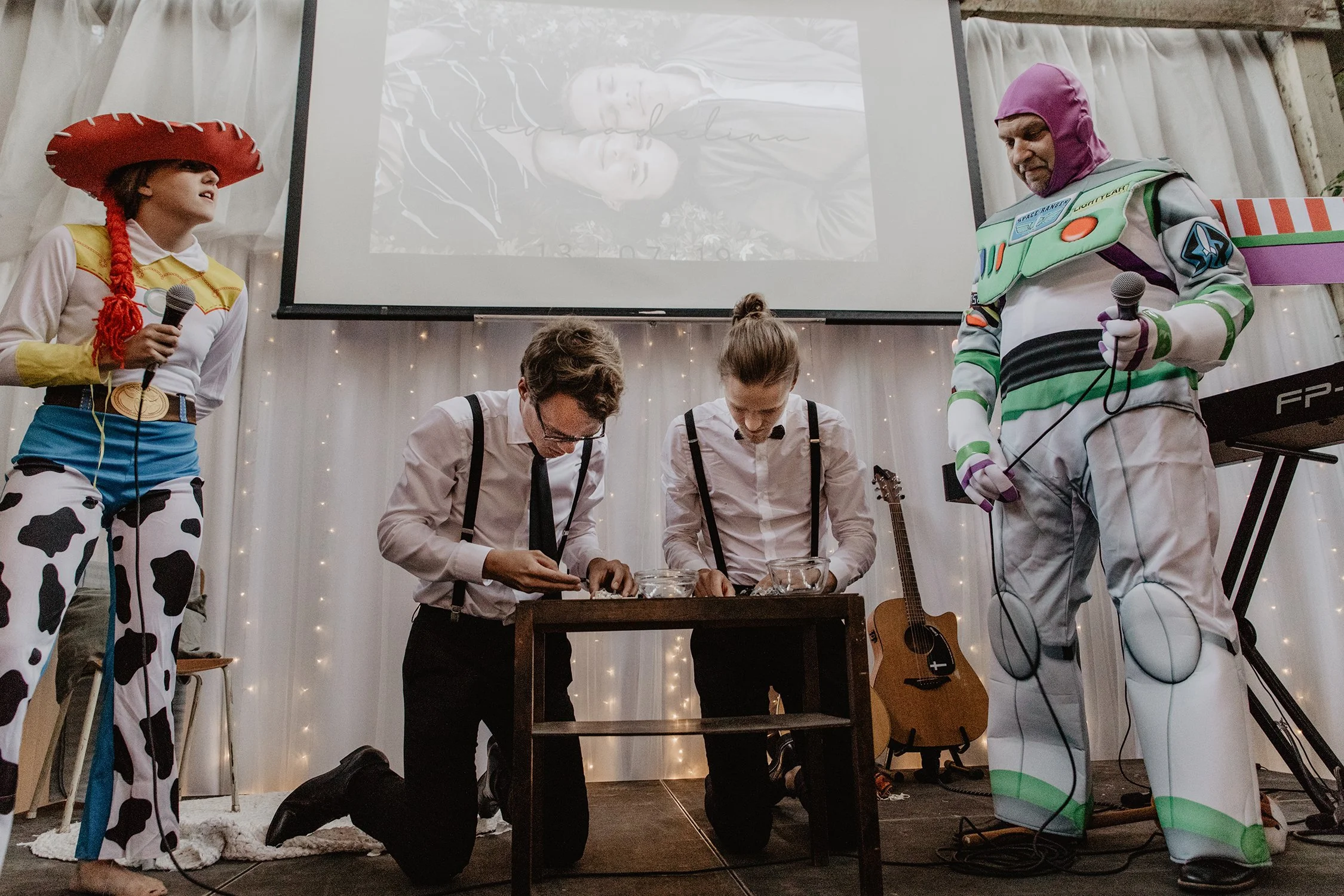 Brudgummens föräldrar har ett scenframträdande på en scen. Pappan är klädd i Buzz Lightyear-kostym och mamman i Woody-kosym. Brugummen och hans bror tävlar.