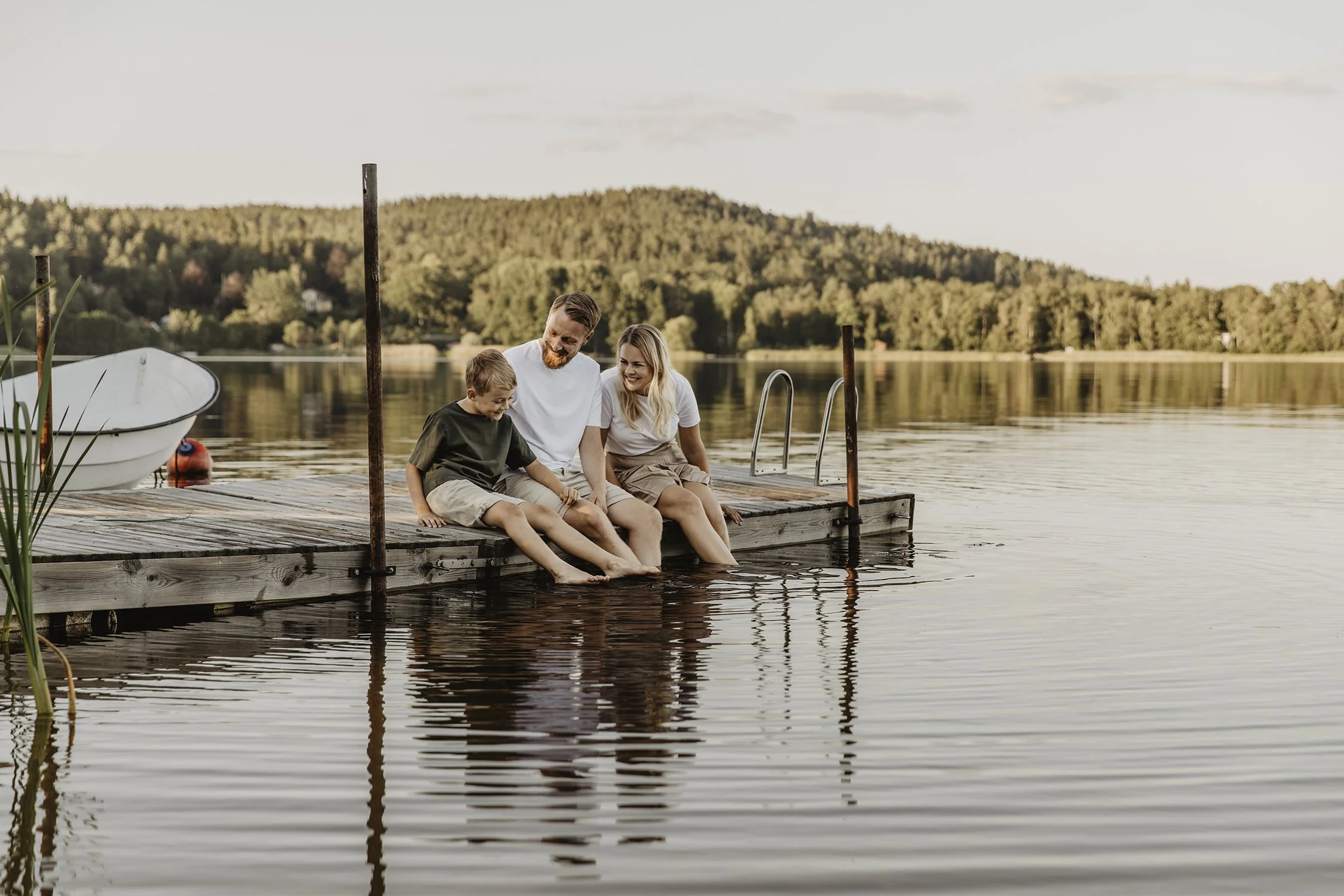 Familj under en familjefotografering som sitter på en brygga vid Bunn och leker och skrattar.