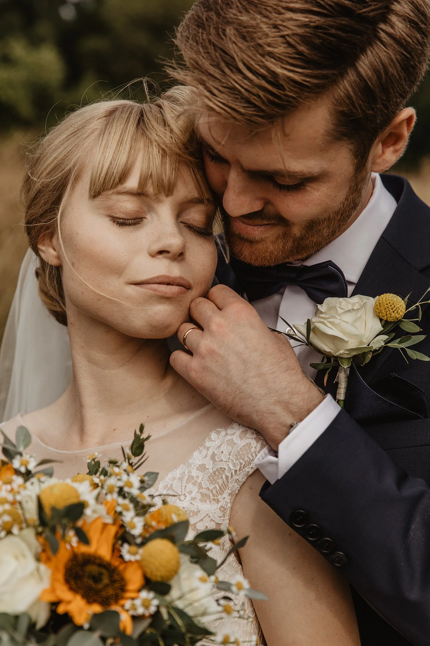 En nygift brud och brudgum som delar ett intimt ögonblick ute i naturen, omgivna av blommor.