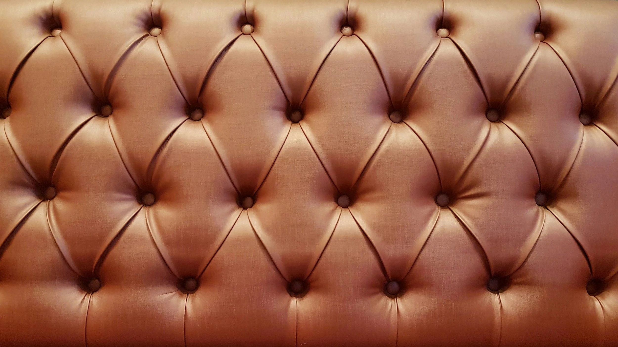 Close-up of a tufted, upholstered fabric with a diamond pattern and button details.