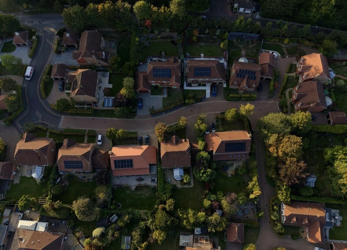 Aerial view of a neighborhood with houses, trees, and winding roads.