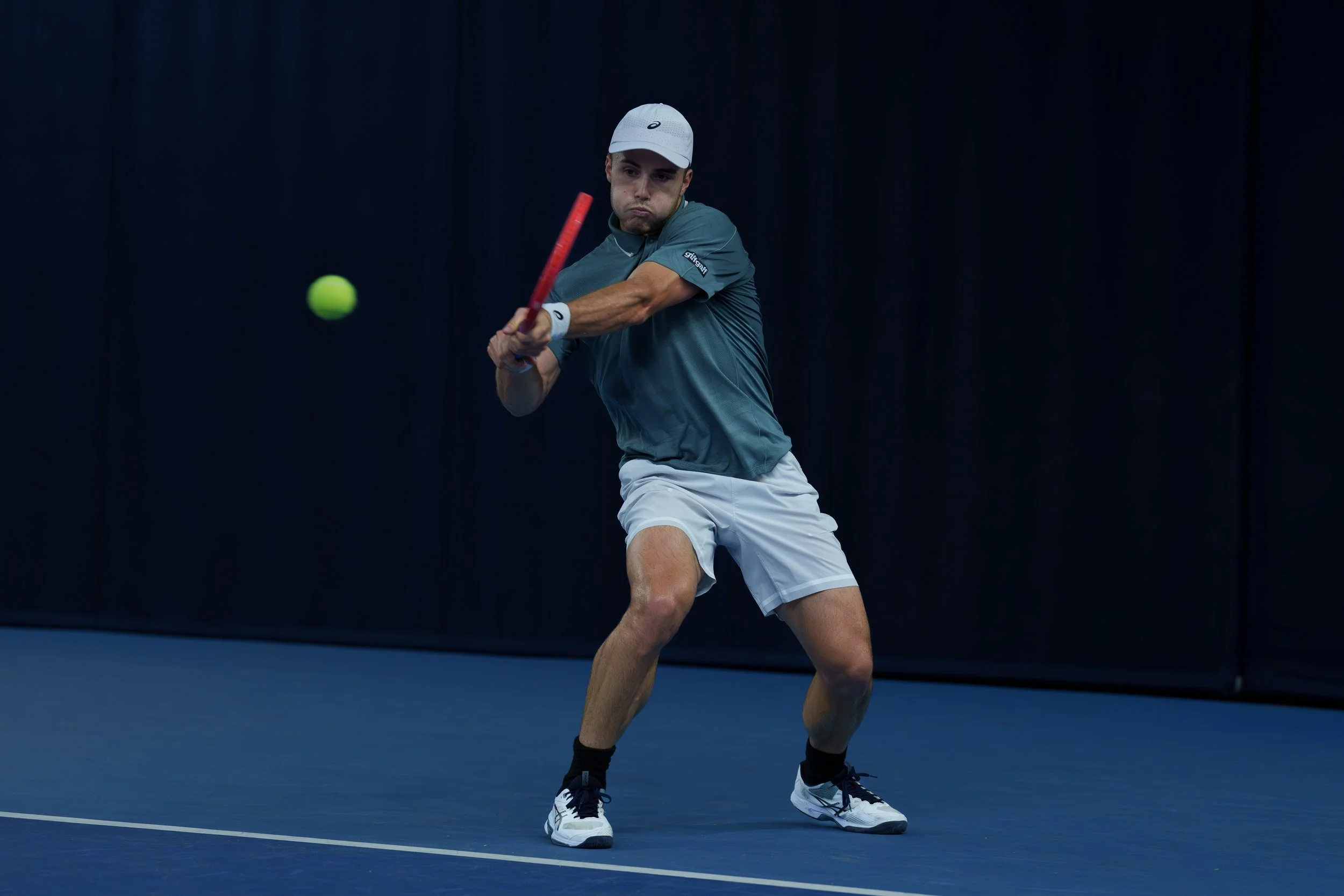 Arthur Fery hitting a ball with a red racket Great Britain at the Davis Cup.