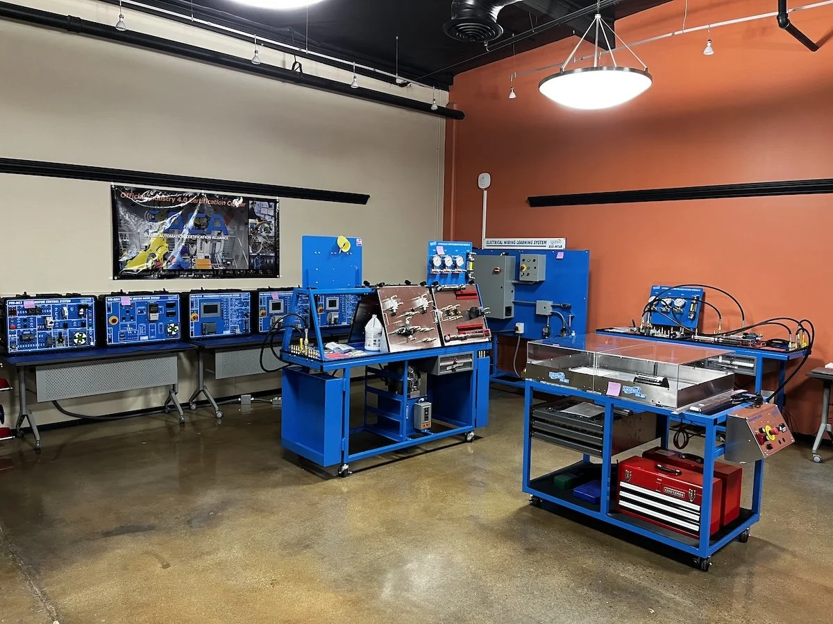 Educational robotics classroom with blue workbenches, testing equipment, and instructional display screens.