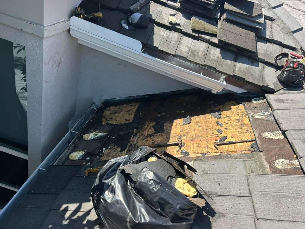 Rooftop with shingles, roofing tools, and insulation materials, some areas under repair or construction.