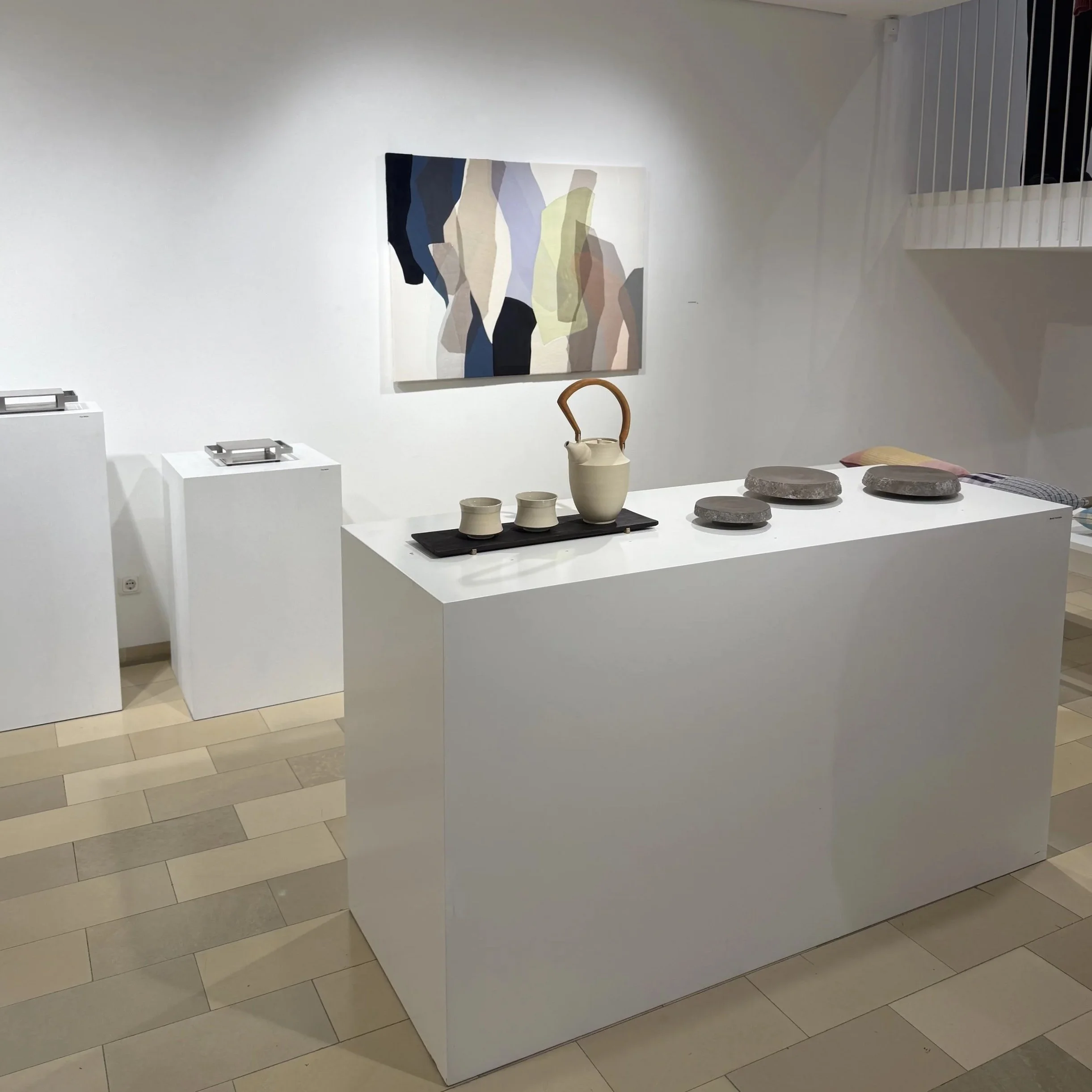 Arbeiten des Künstlers Moritz Frohnhöfer in der Galerie Handwerk in München. Teekannen-Service bestehend aus Teekanne mit Holzgriff, zwei Teeschalen und Holztablett aus geflämmter Eiche. Dazu drei Servierteller aus dunkelgrauem Ton mit reliefartigem