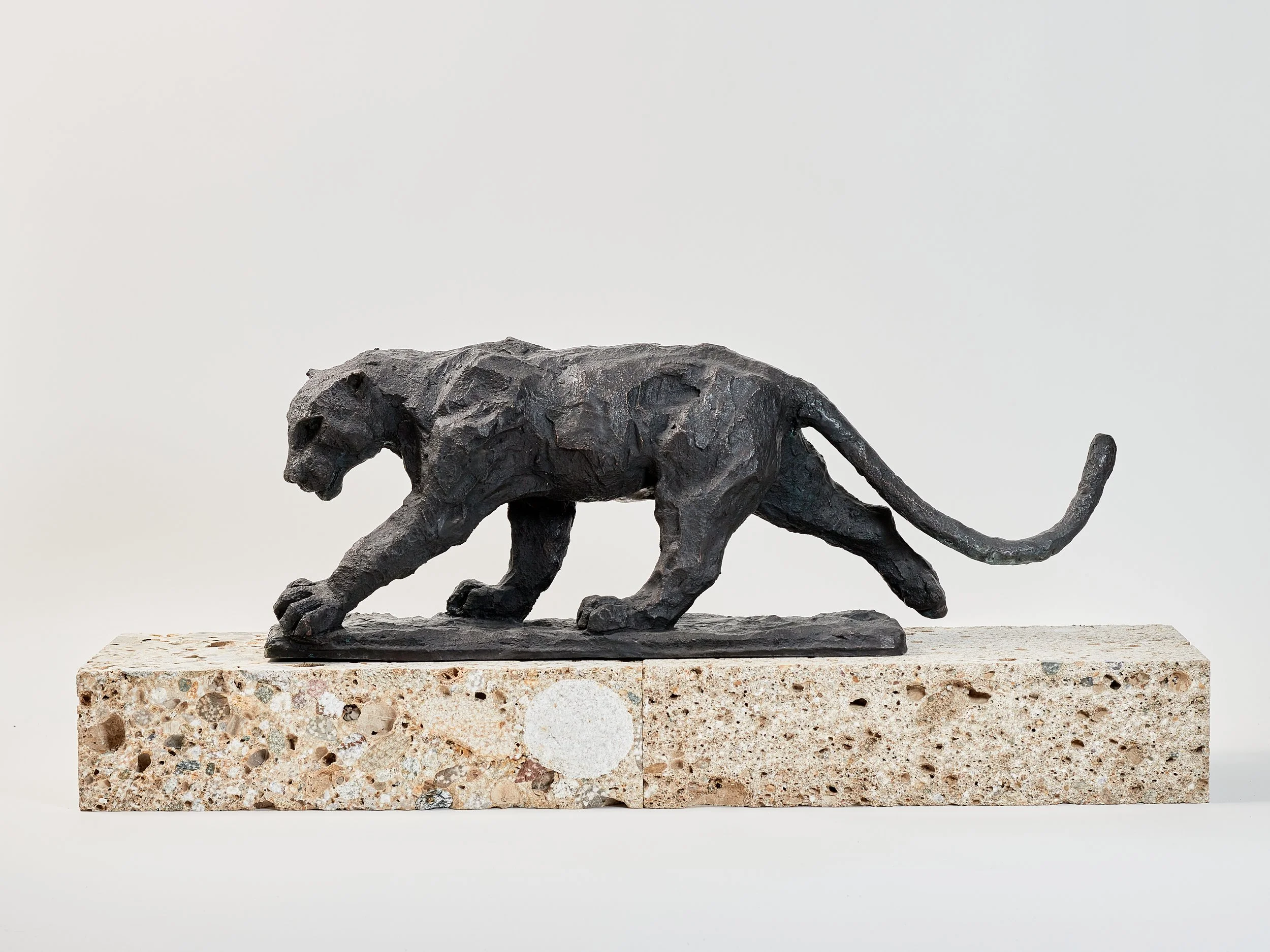 Schreitender, eleganter Panther aus Bronze auf Steinsockel vor hellem Hintergrund