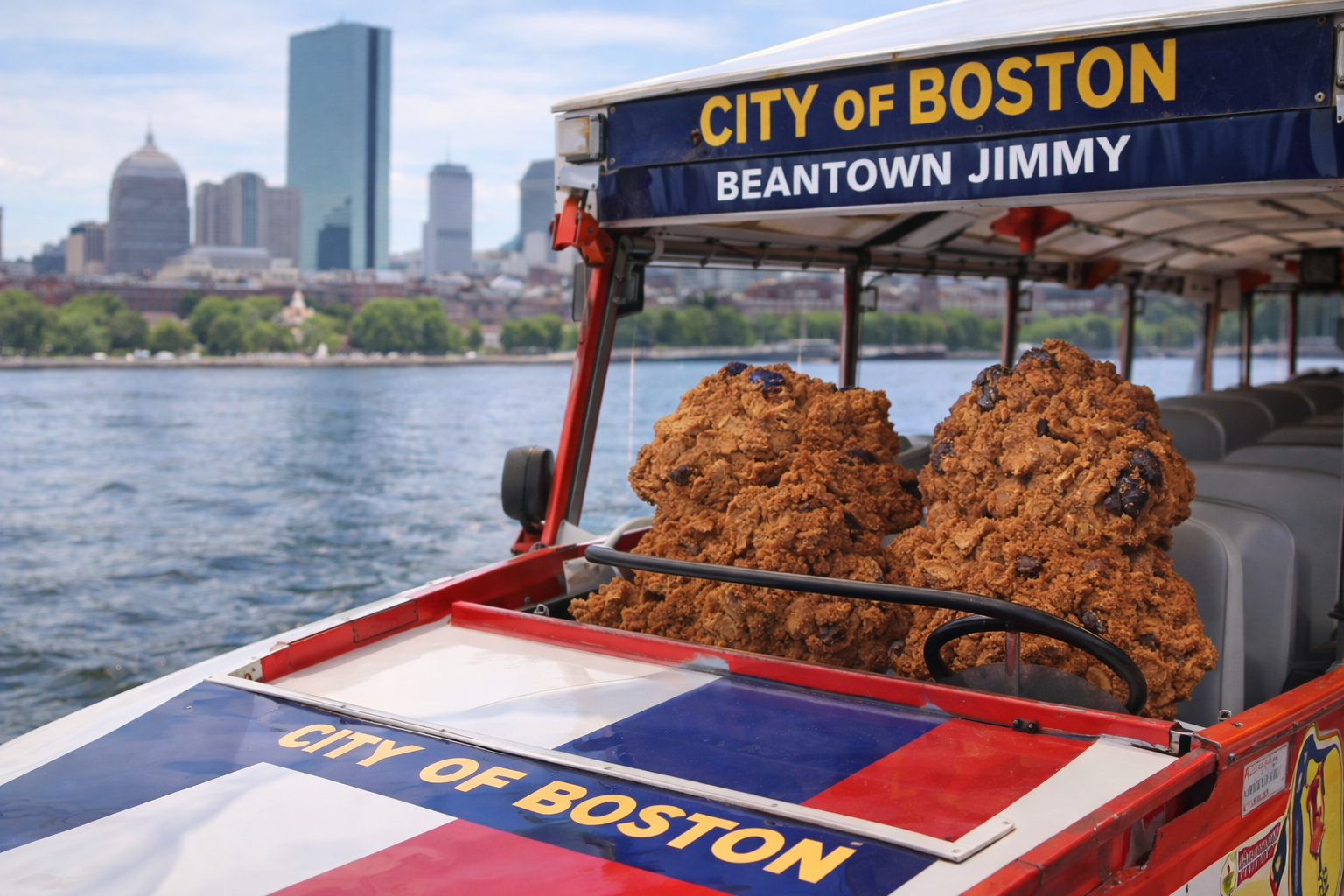 A city boat from Boston harbor filled with large pieces of fried chicken, with the Boston skyline in the background.