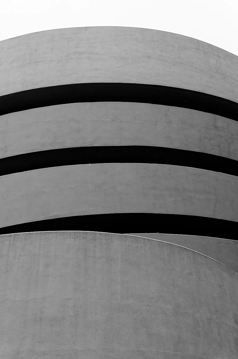 Close-up of a modern concrete building with curved arch-like structures, minimalistic design, black and white photography.