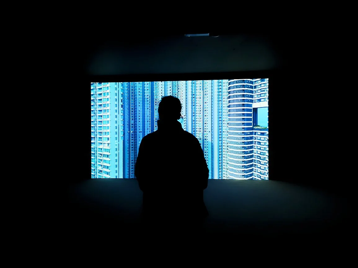 En person står foran en skjerm som viser høye, moderne skyskrapere i en by.