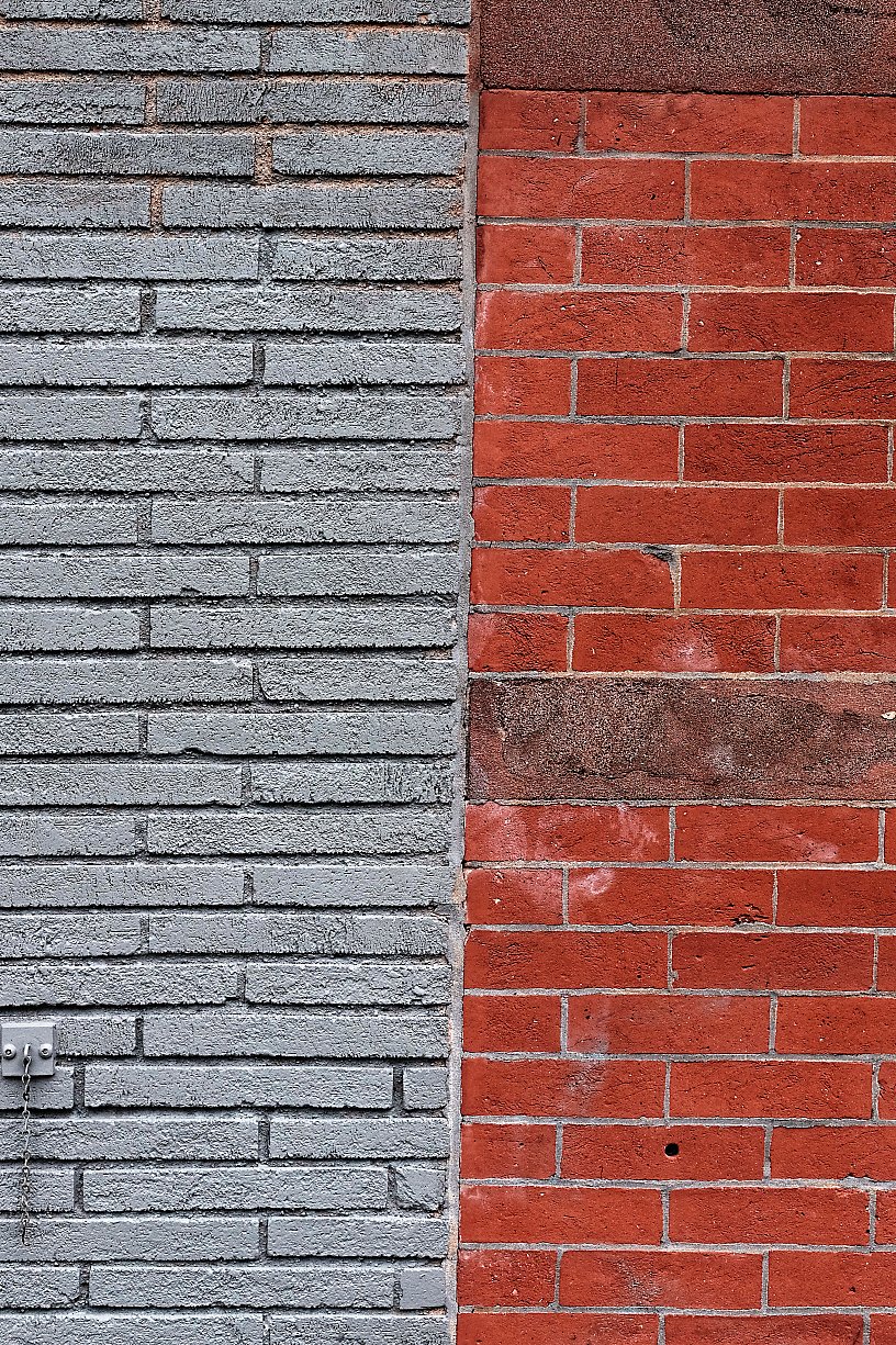 Photo of two different brick walls, one gray on the left and one red on the right, separated by a vertical line.