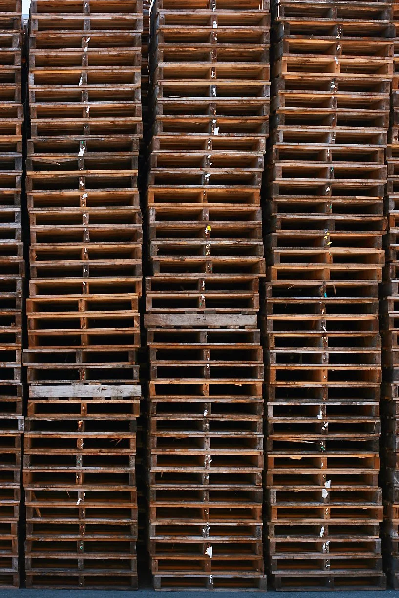 Multiple stacks of empty wooden pallets arranged vertically.