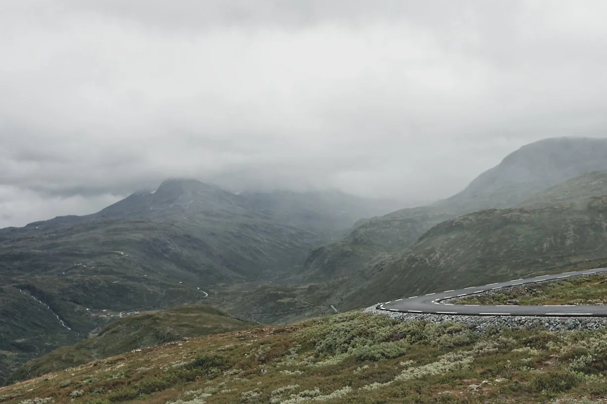 En vei som svinger rundt fjell i et avsidesliggende landskap under overskyet vær.