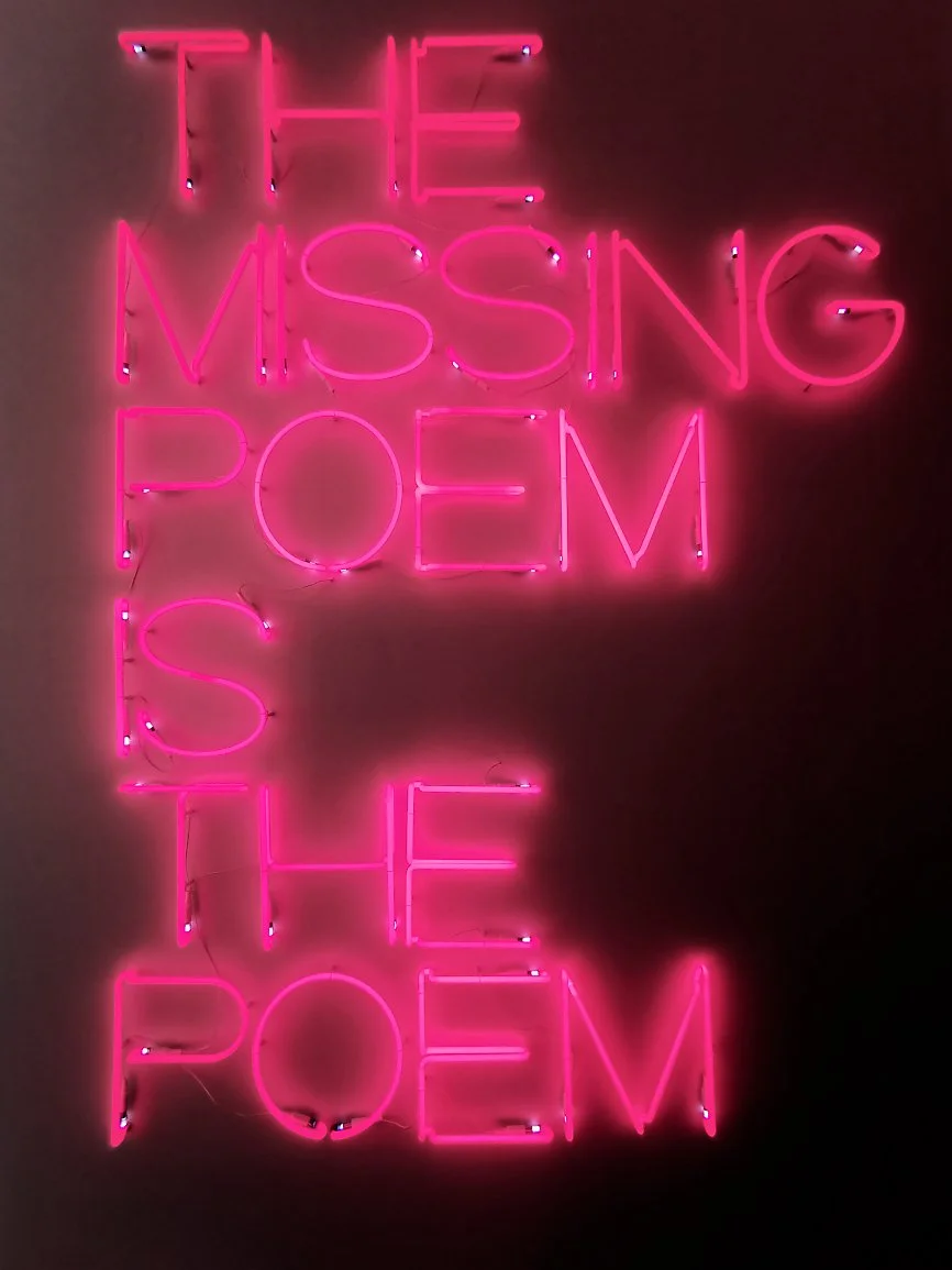 Neon skilt som sier 'The Missing Pomegranate' i rosa farger.