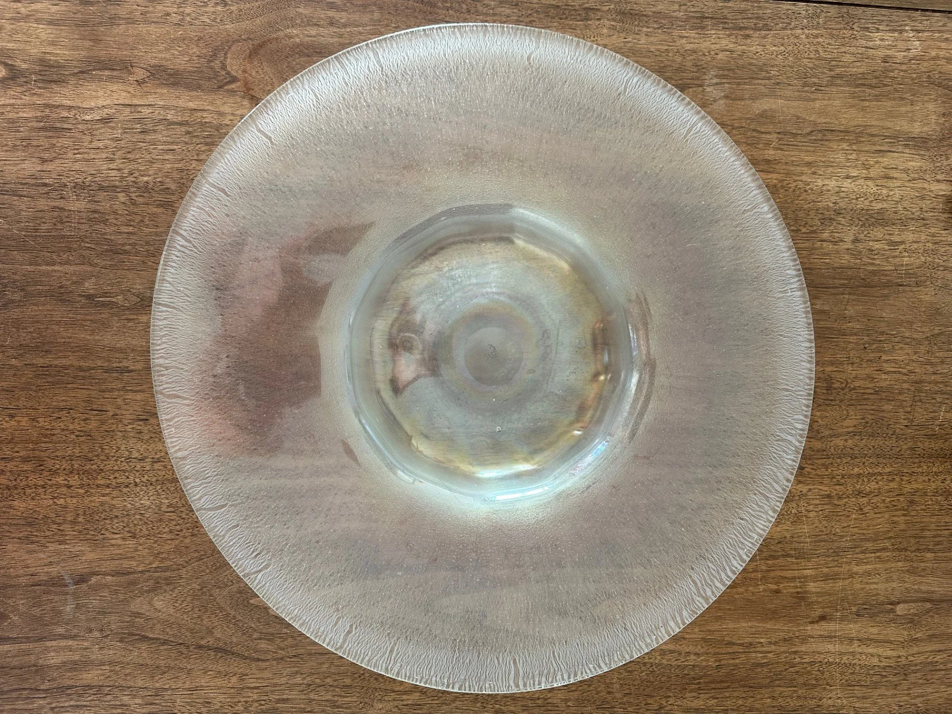 Empty transparent glass bowl on a wooden surface.