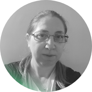 Foto di una donna con capelli legati, occhiali, in un ambiente interno in bianco e nero.