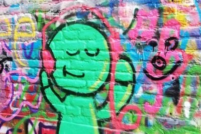 murale di un volto stilizzato con occhi chiusi e sorriso, in stile graffiti colorato