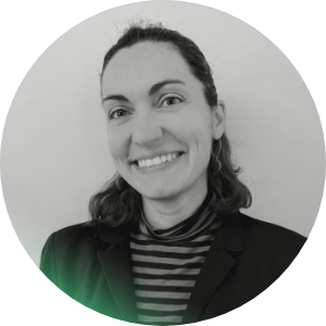 Una donna sorridente con capelli scuri in un abito nero e una maglietta a righe, foto in bianco e nero.