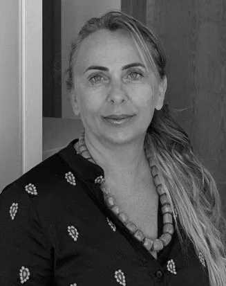 ritratto di donna con capelli lunghi raccolti e abbigliamento scuro con motivo a fiore, sfondo di una porta di legno