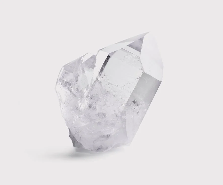 A clear, irregularly shaped crystal or piece of quartz on a plain white background.