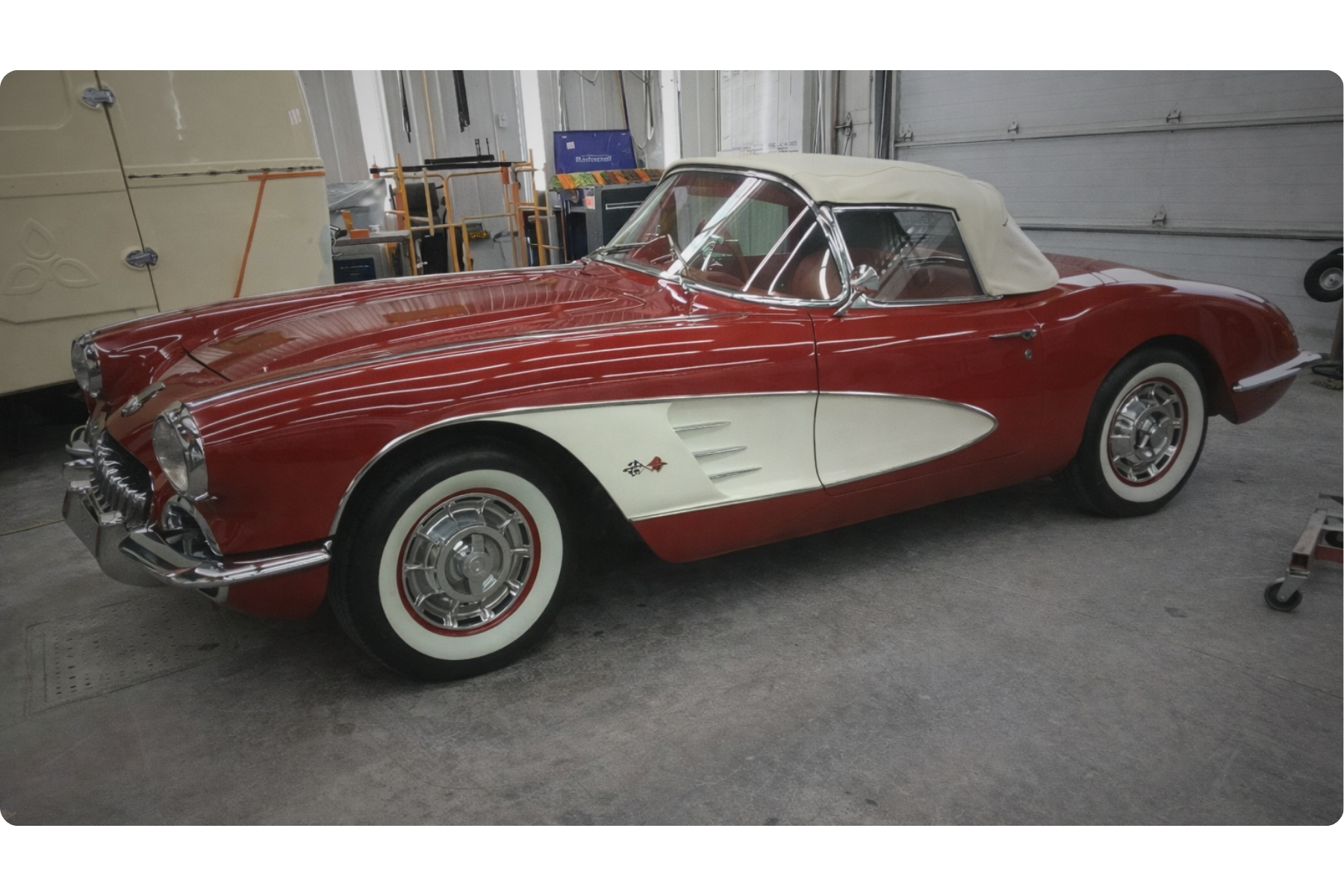 Voiture de collection rouge et blanche, berline cabriolet, dans un garage, à l'intérieur