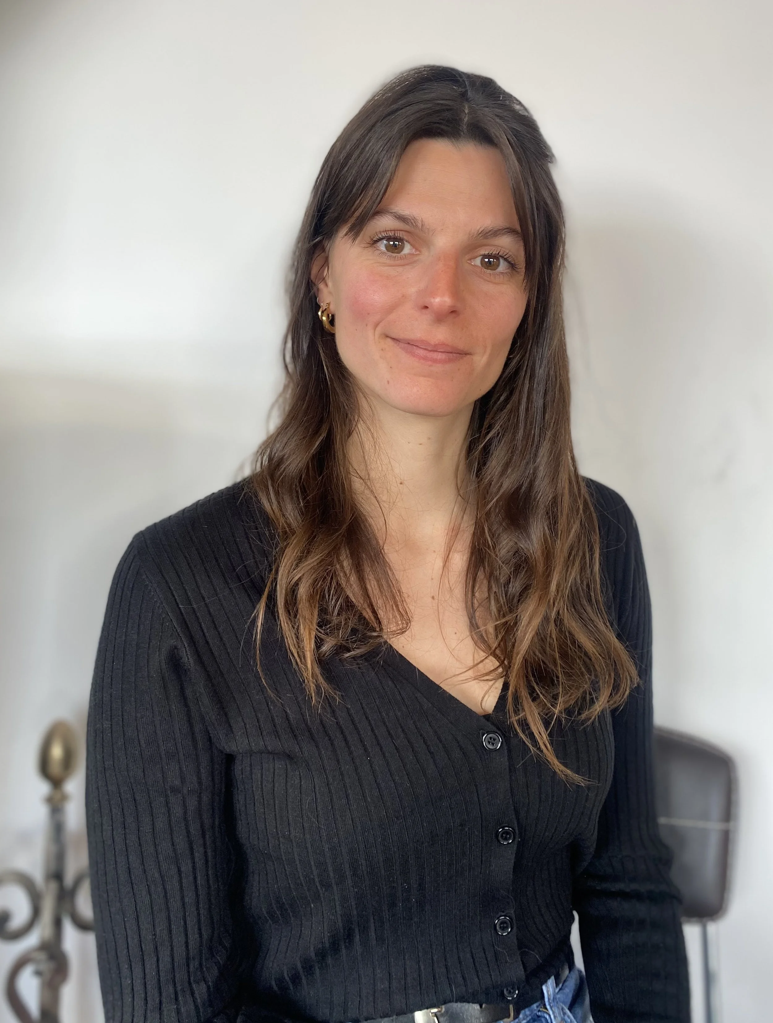 Photo de Marianne Berger-By, psychologue spécialisée en Thérapies cognitives et comportementales : Une femme avec des cheveux bruns, souriant légèrement et chaleuresement dans un intérieur avec un mur blanc en arrière-plan.