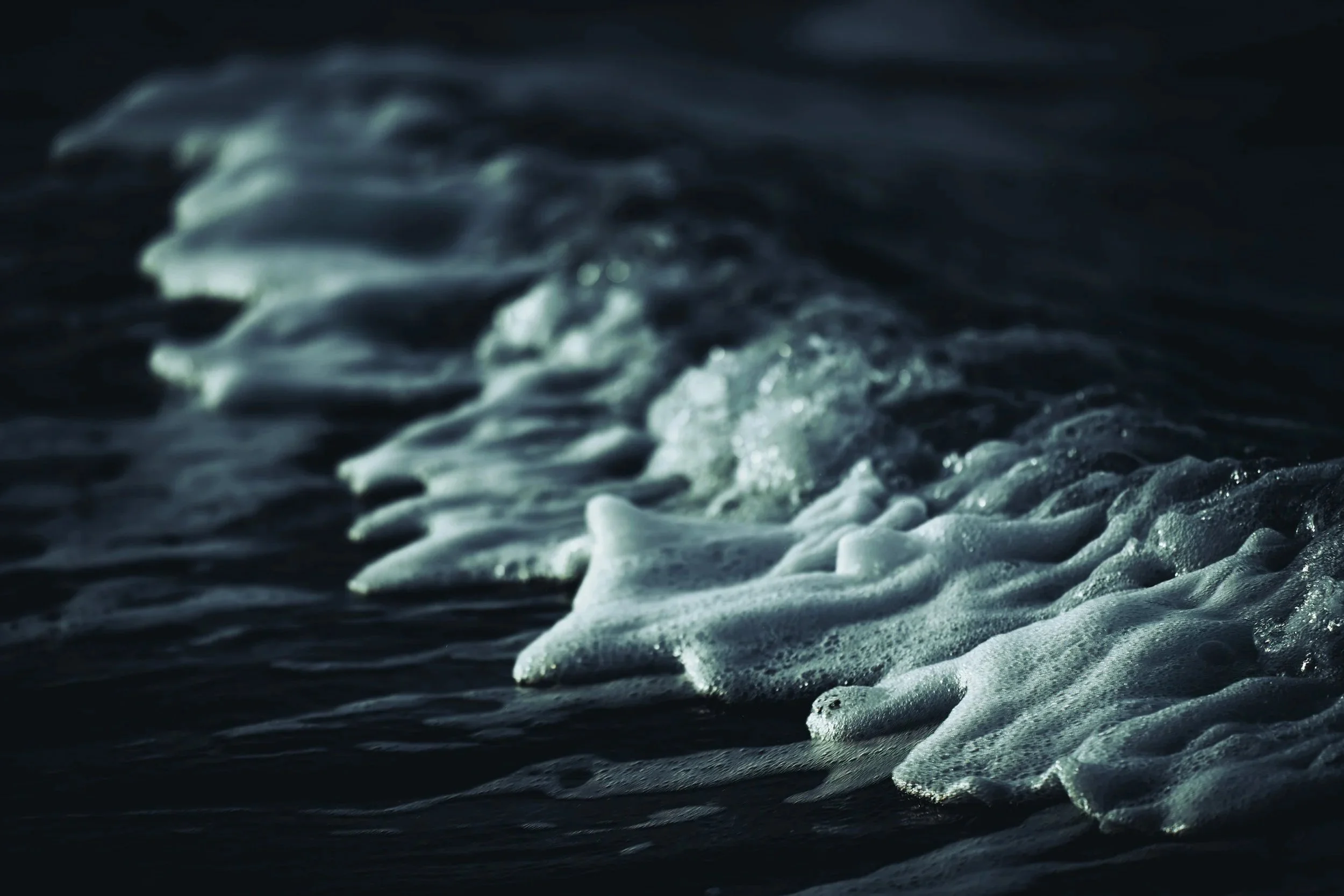 Close-up of ocean waves with white foam on dark water.