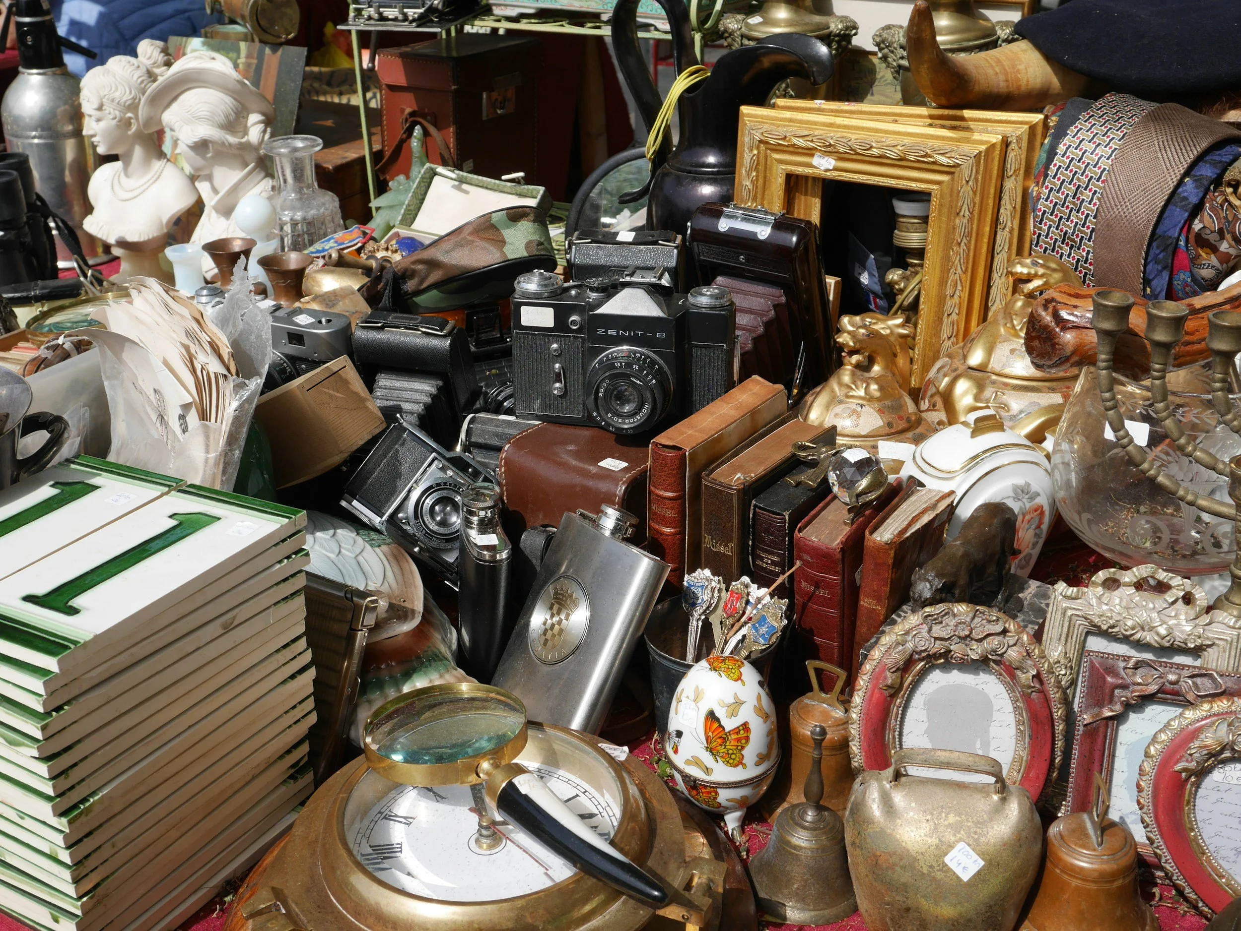 A collection of vintage and antique items including cameras, picture frames, ceramics, books, jewelry, and decorative objects.