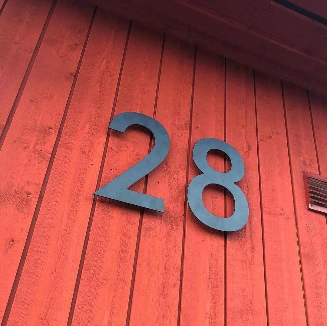 Husnummer 28 i mørkegrå stål på rød træterrasse