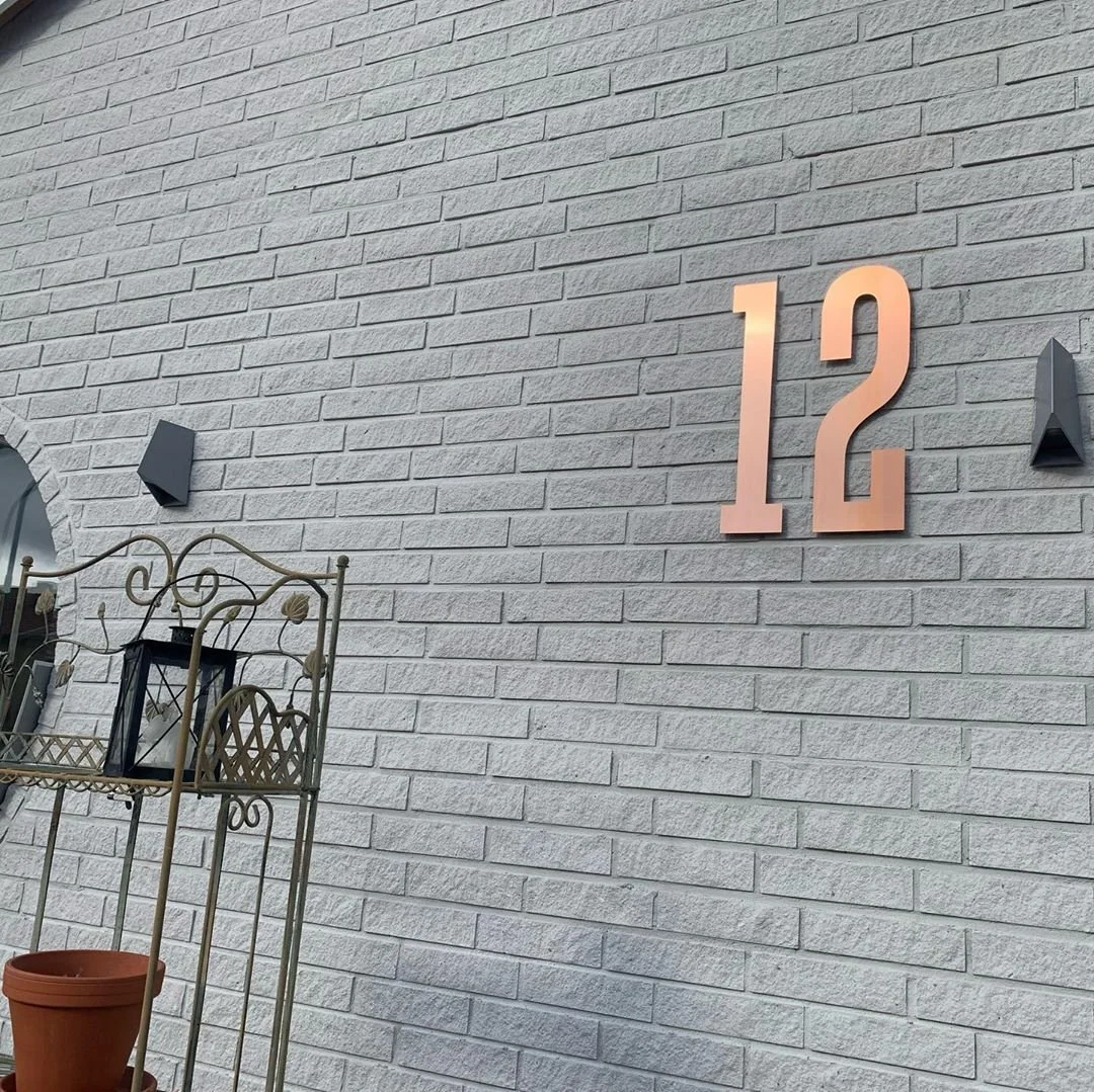 Husnummer 12 i kobber på grå naturstensfacade