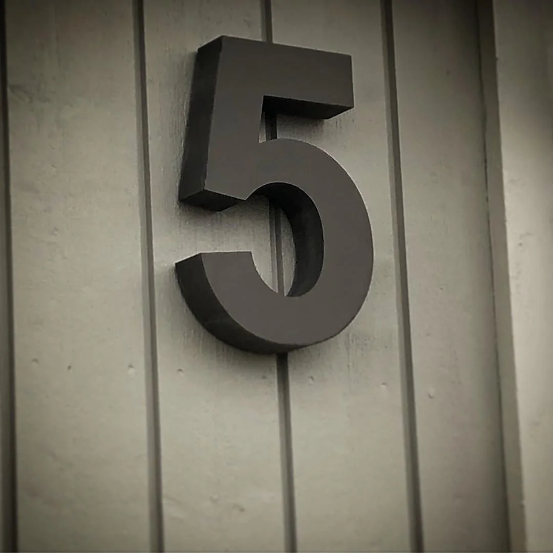 Husnummer 5 i mørkgrå stål på træpanelfacade