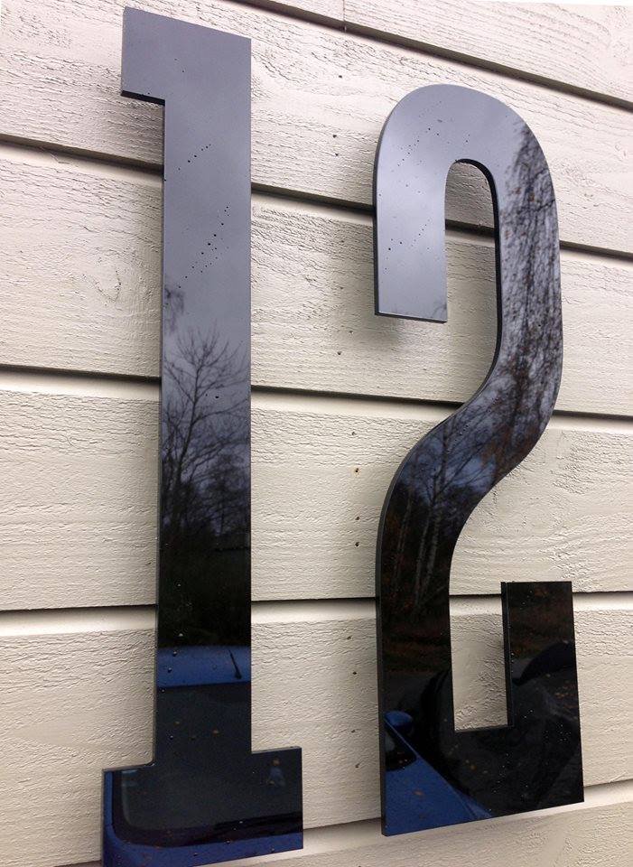 Husnummer 12 i sort akryl på bleg naturstensfacade