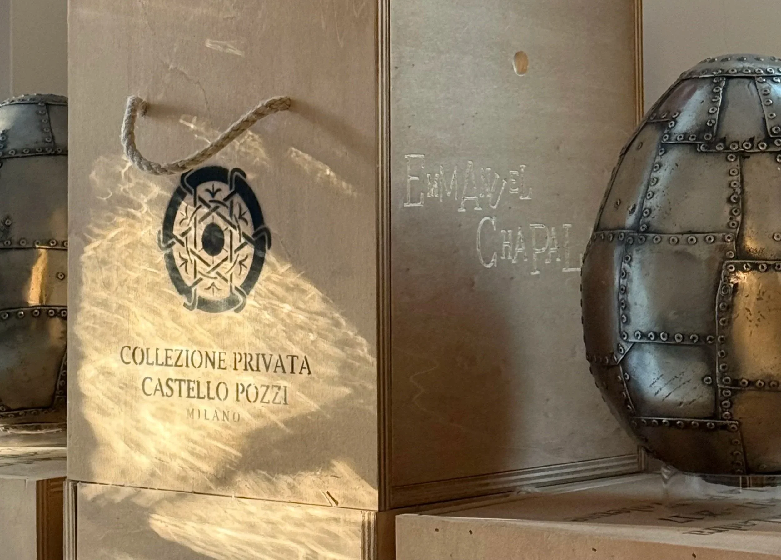 Immagine di una parete con un poster di una collezione privata di un castello a Pizzo, Milano, e un'armatura decorativa in metallo rivettata su entrambi i lati.