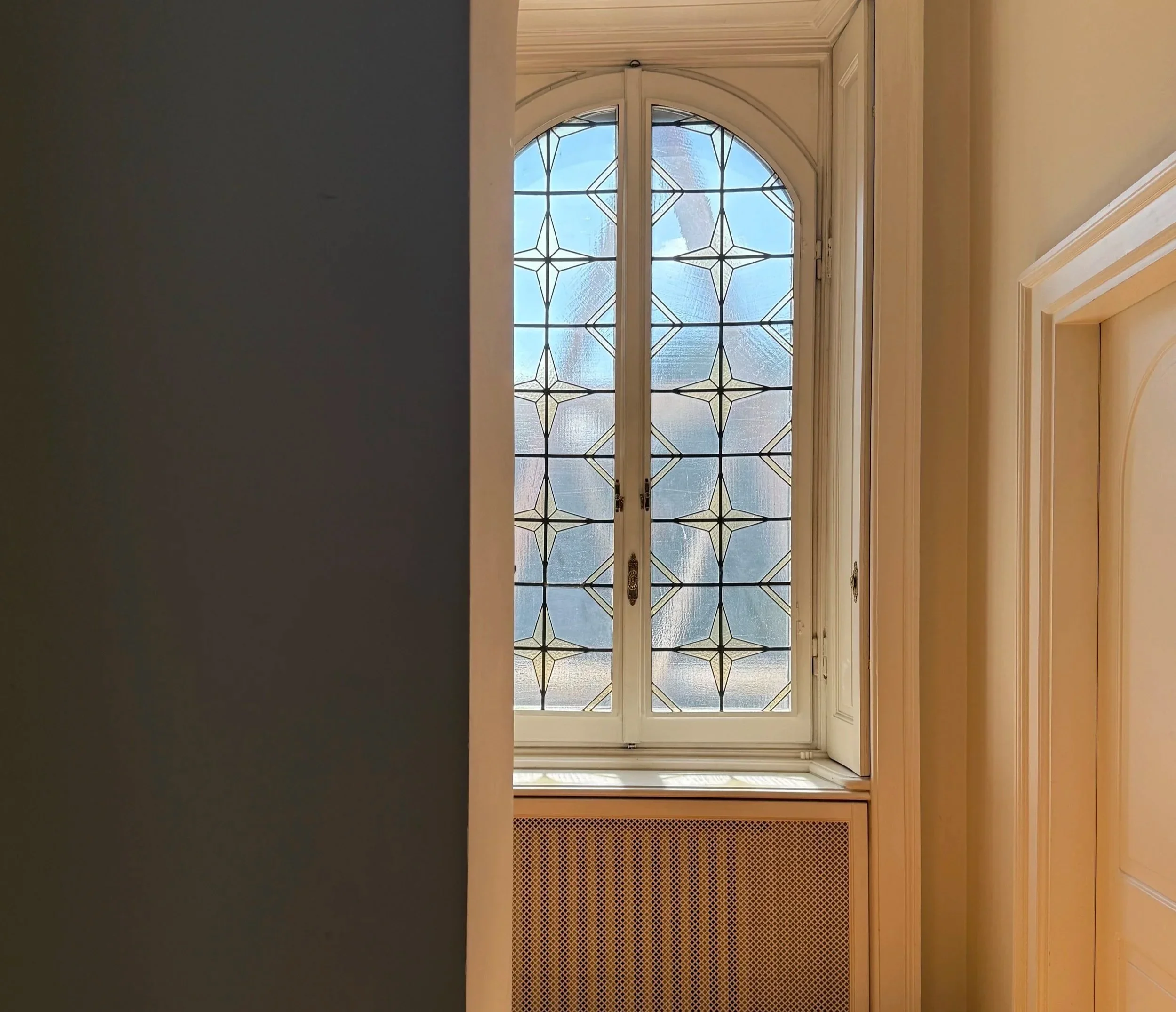 Finestra decorativa con vetri colorati e geometrie, con vista sul cielo.