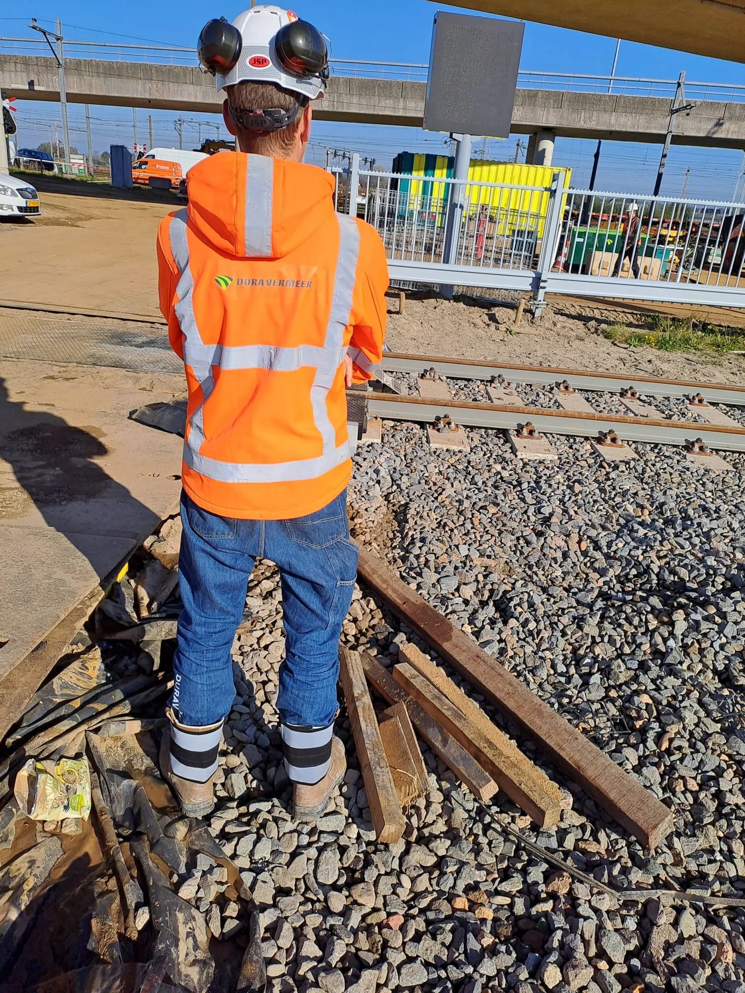 Spoormedewerker in oranje hi-vis vest en RefLegs enkelreflectoren op spoorbed